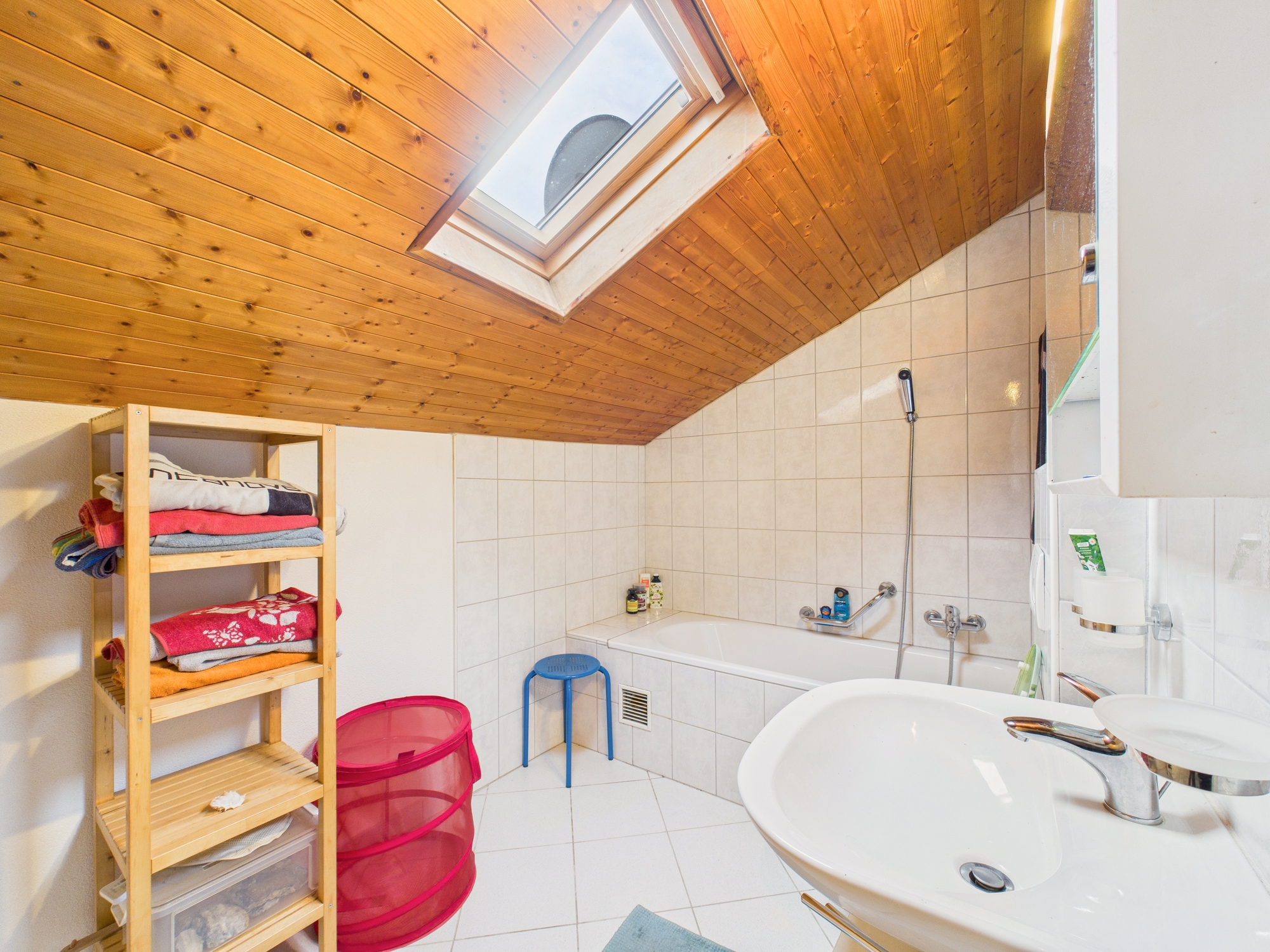 Dachgeschoss-Badezimmer mit Badewanne und Dachfenster