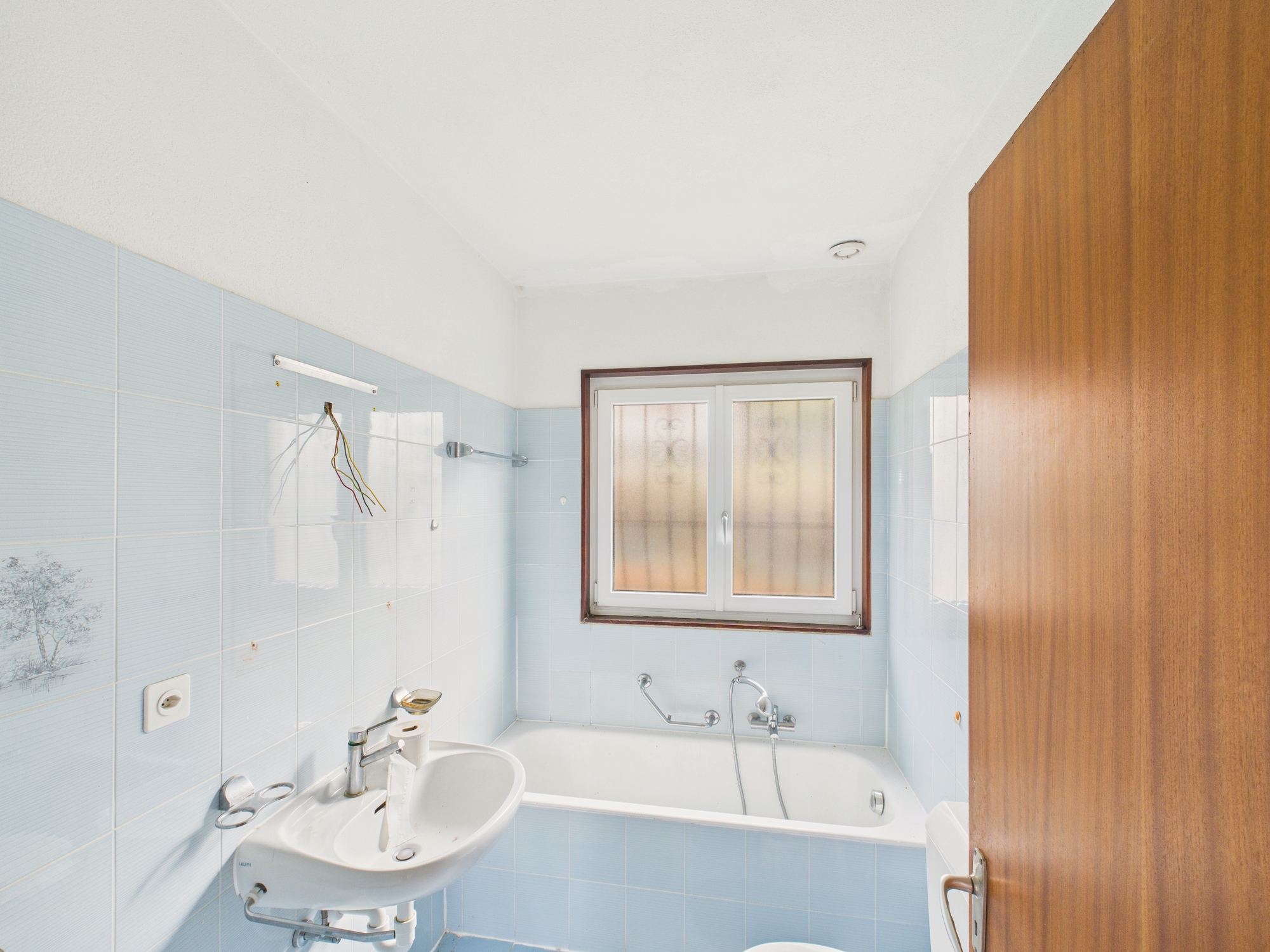 Kleines, helles Badezimmer mit Badewanne und Waschbecken
