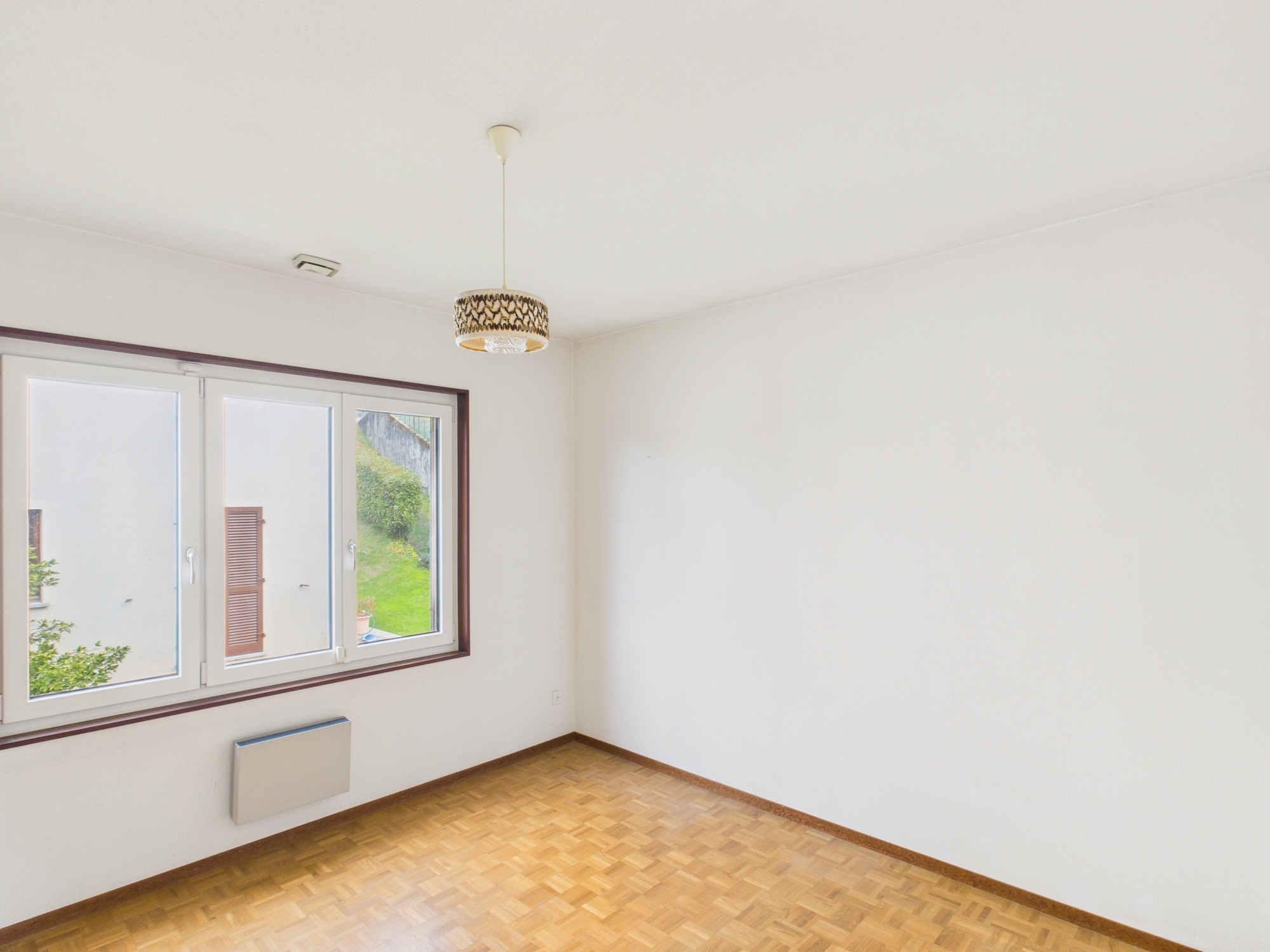 Leerer, heller Raum mit Fenster und Pendelleuchte