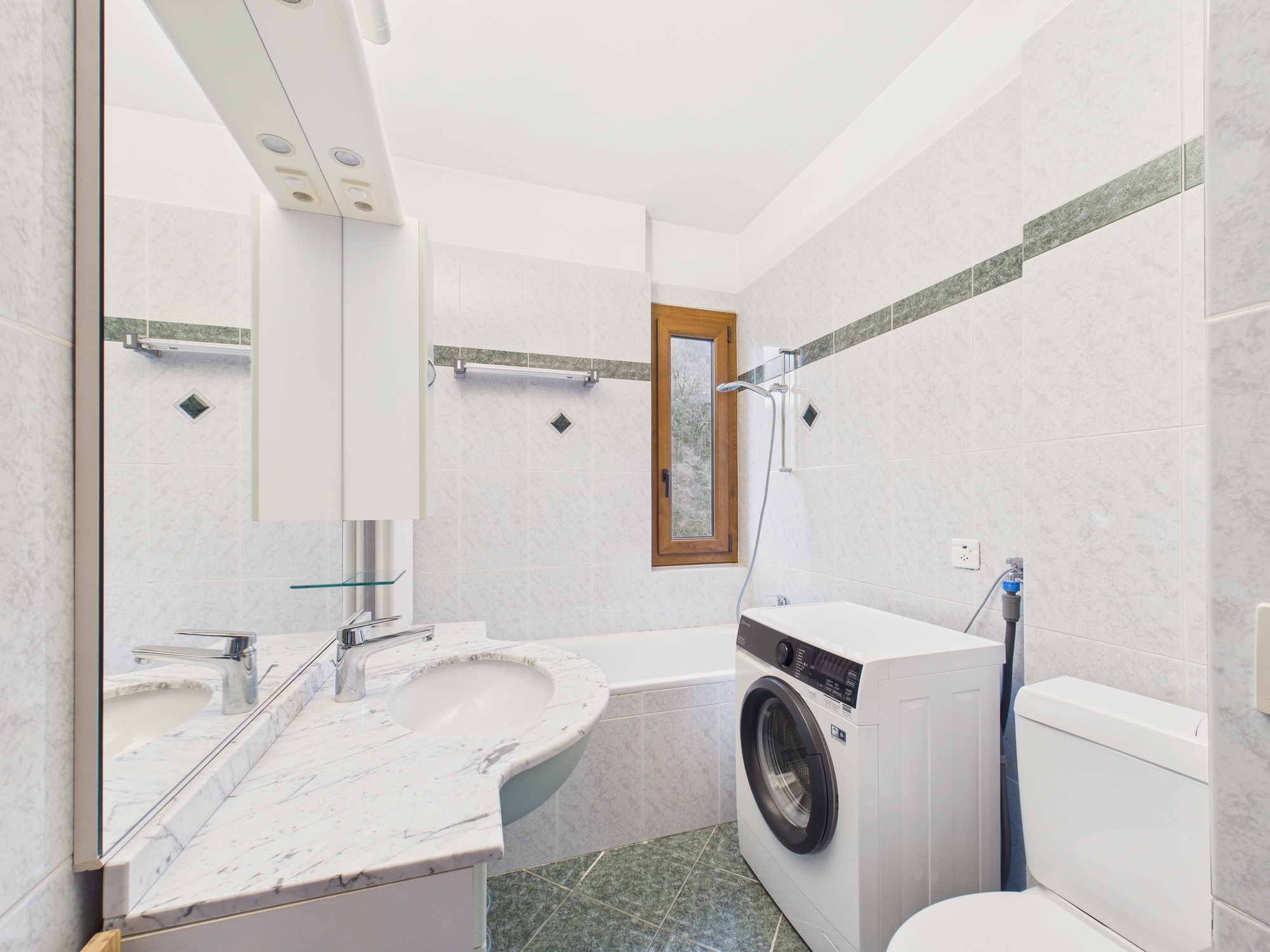 Badezimmer mit Waschmaschine und Badewanne