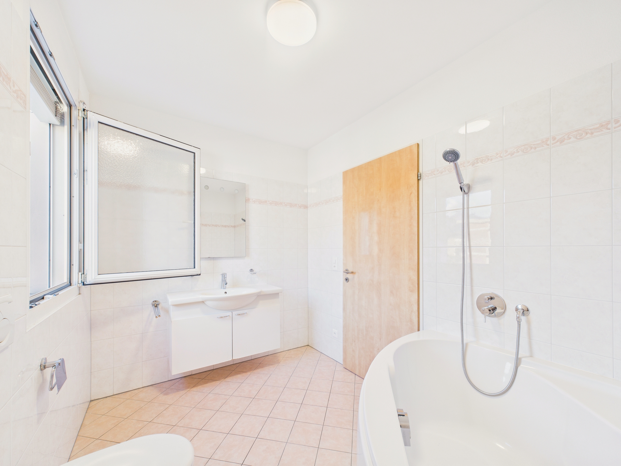 Helles, schlichtes Badezimmer mit Wanne und Fenster