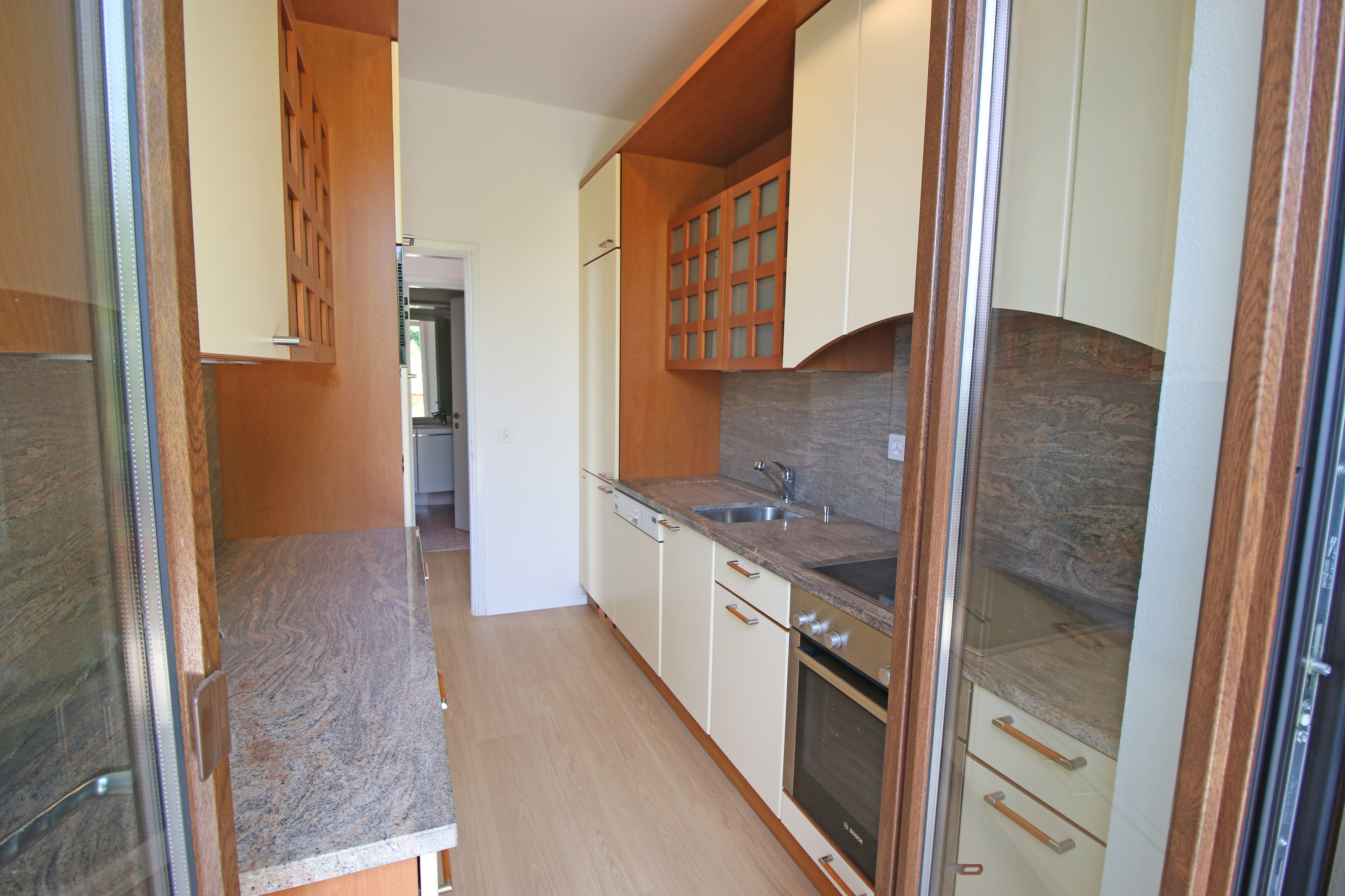 Schmale, gut ausgestattete Küche mit Holz- und Cremefronten