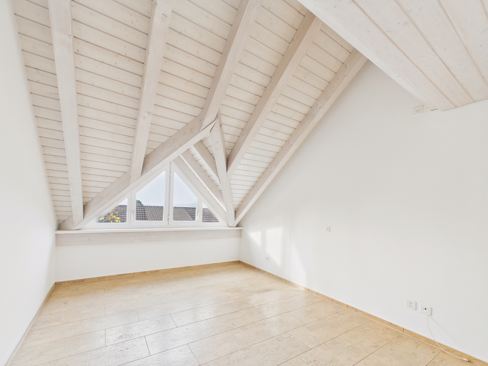 Heller Dachgeschossraum mit sichtbaren Holzbalken