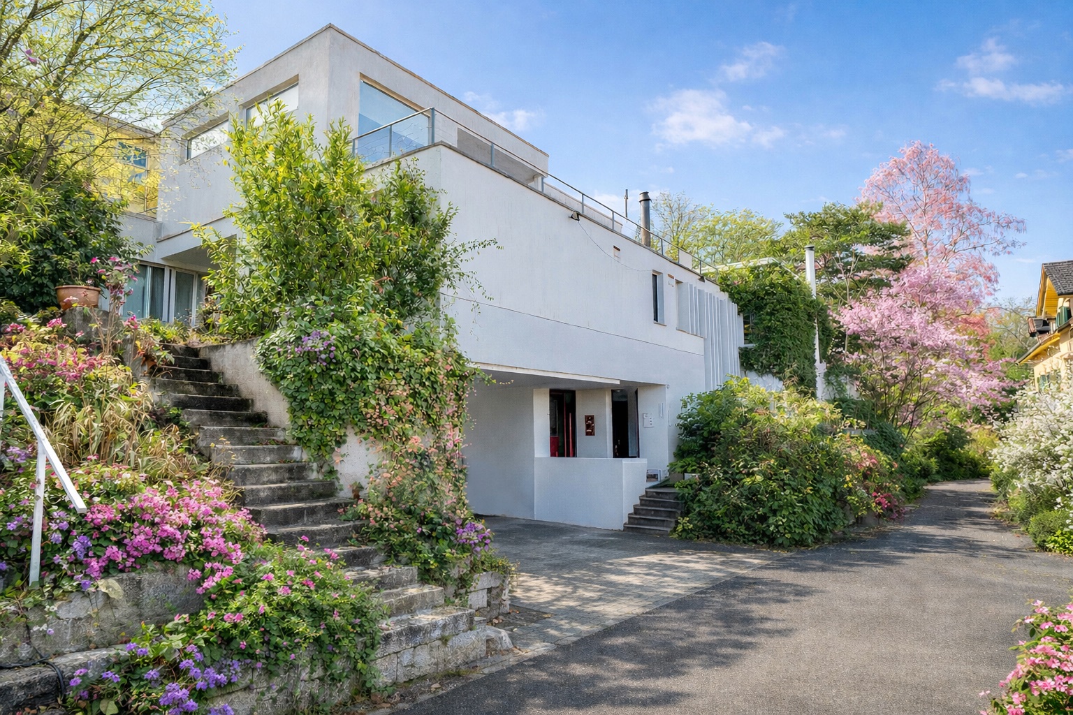 Modernes weißes Haus mit üppiger Gartenbepflanzung