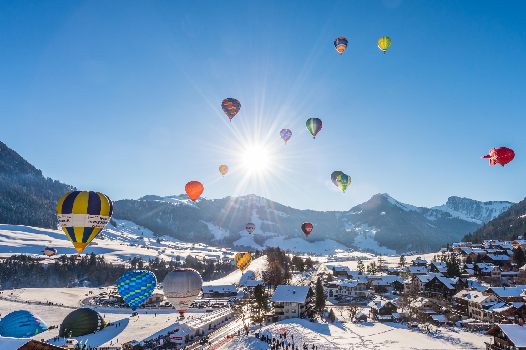 Luftaufnahme eines verschneiten Bergdorfs mit Heißluftballons