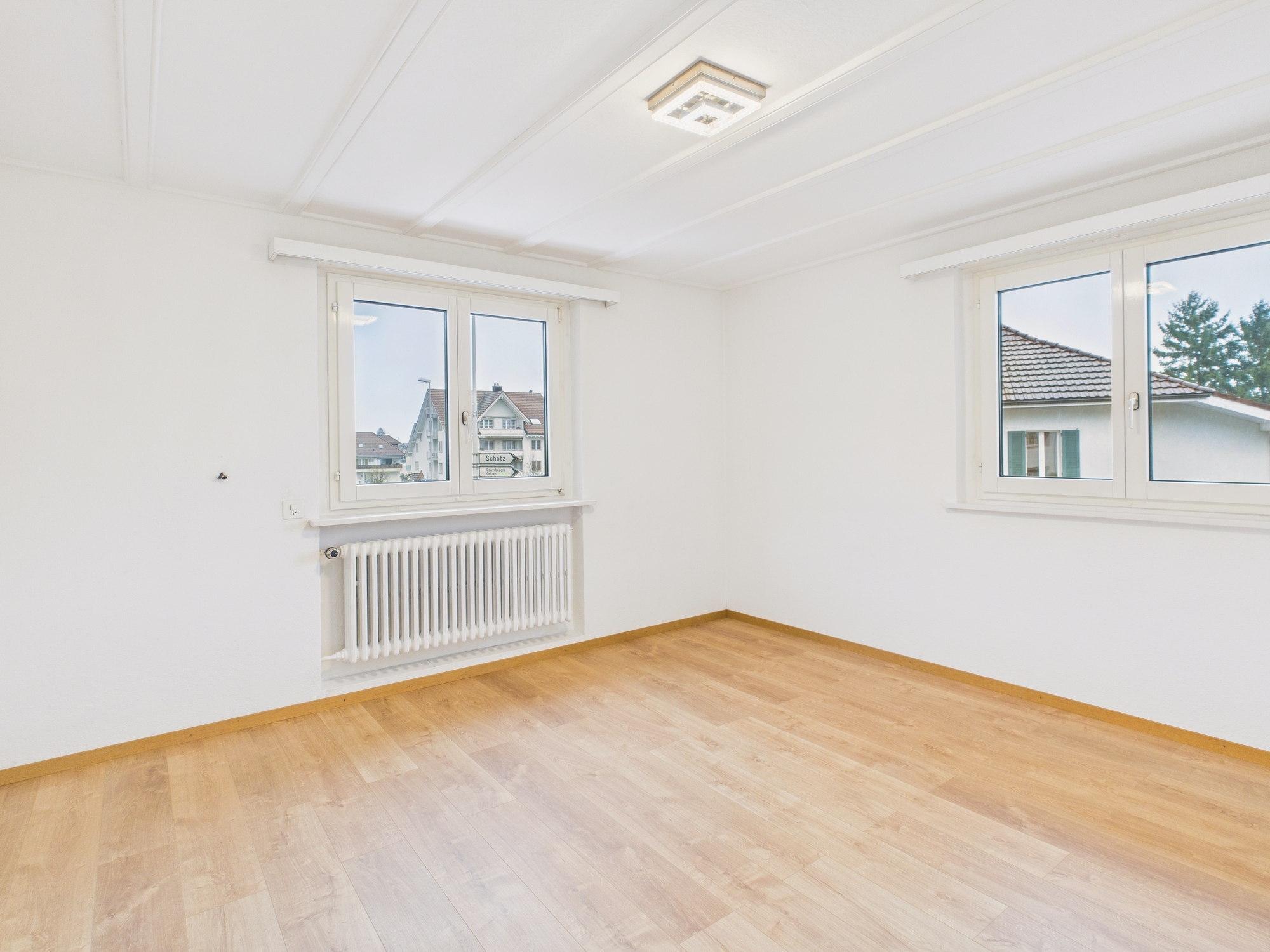 Leeres, helles Zimmer mit zwei Fenstern