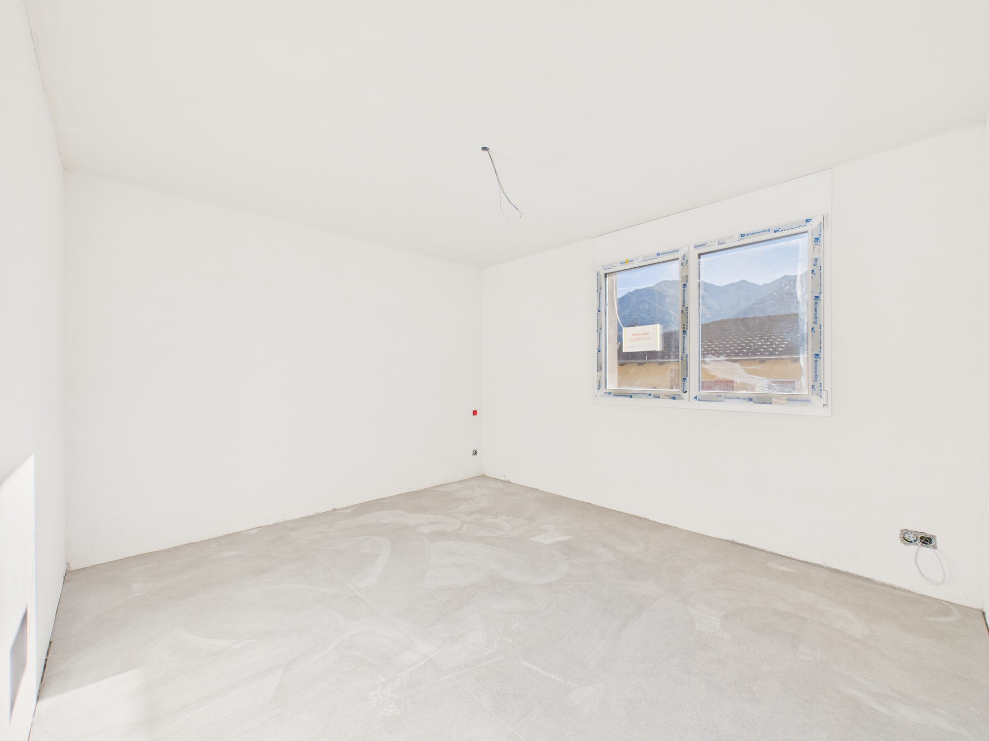 Leerer, frisch verputzter Raum mit Fenster und Bergblick