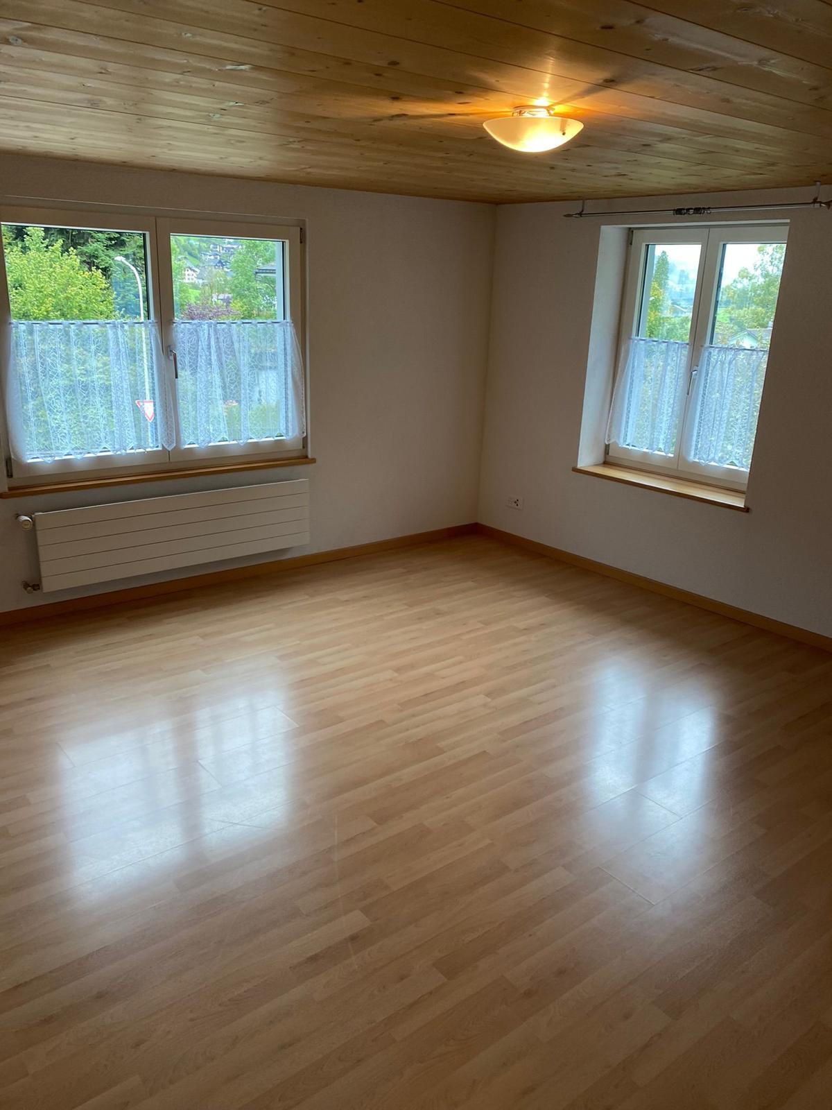 Leeres Zimmer mit Holzdecke und zwei Fenstern