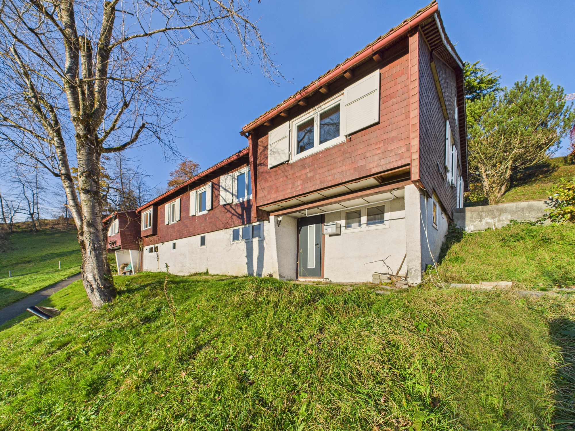 Mehrfamilienhaus im Grünen mit roter Fassadenverkleidung