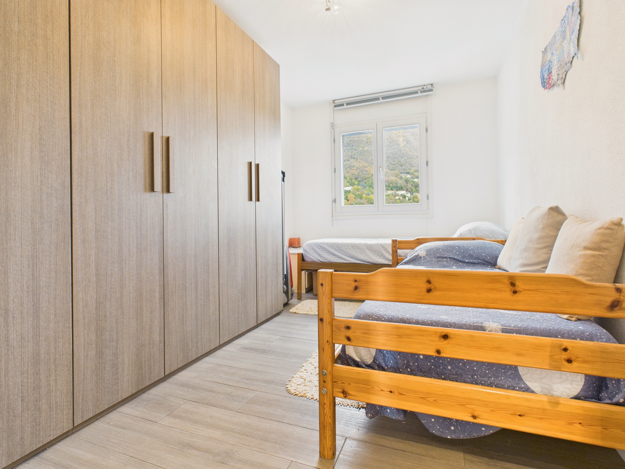 Helles Schlafzimmer mit Holzbetten und großem Einbauschrank