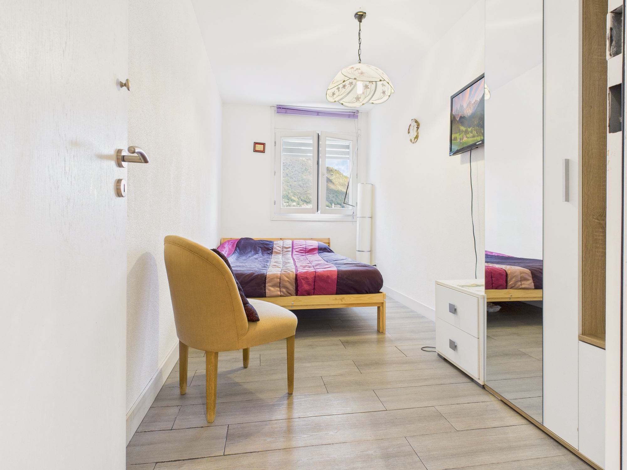 Schmales Schlafzimmer mit Bett und Schrankwand