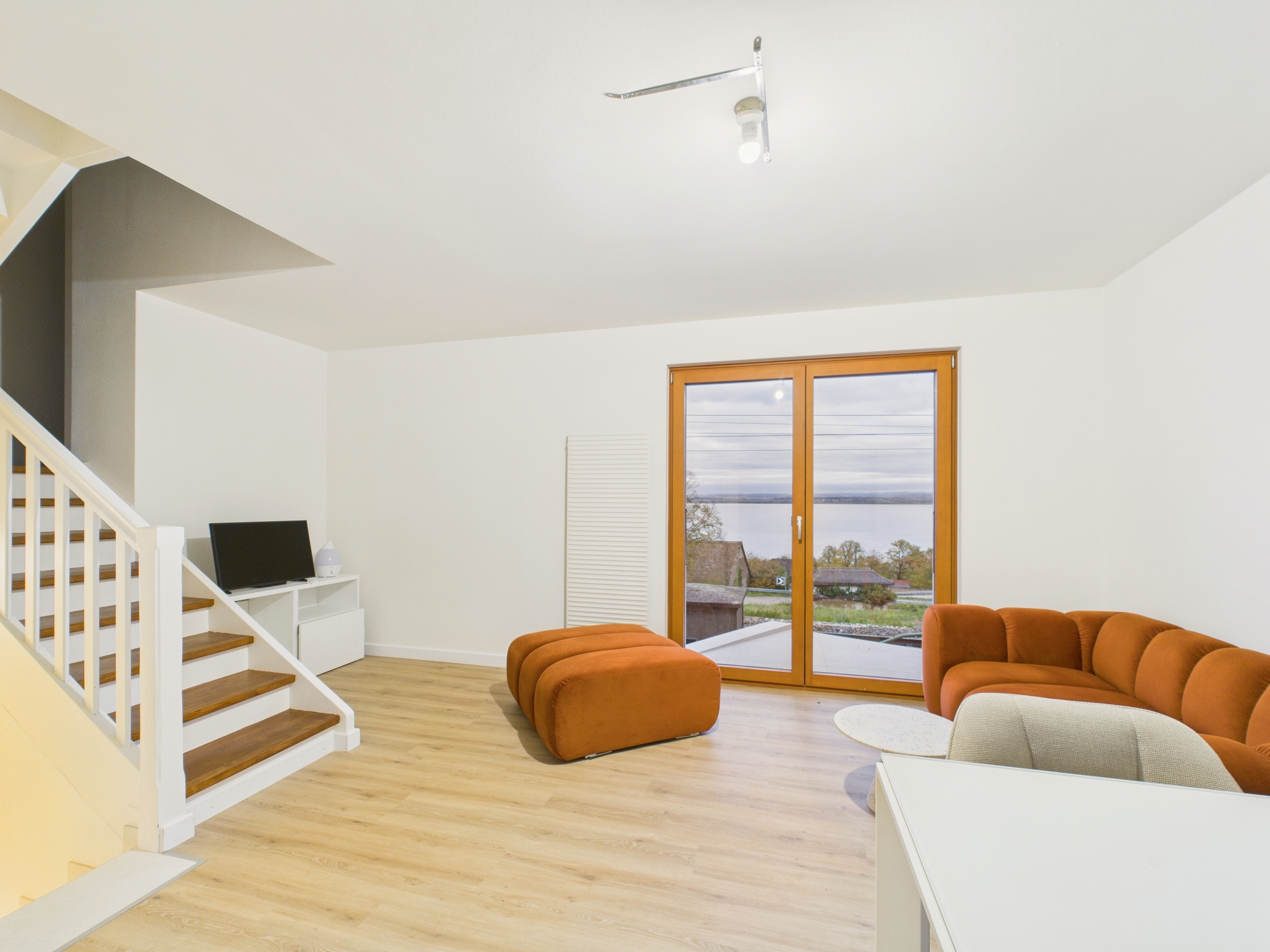 Heller Wohnraum mit Treppe und Seeblick