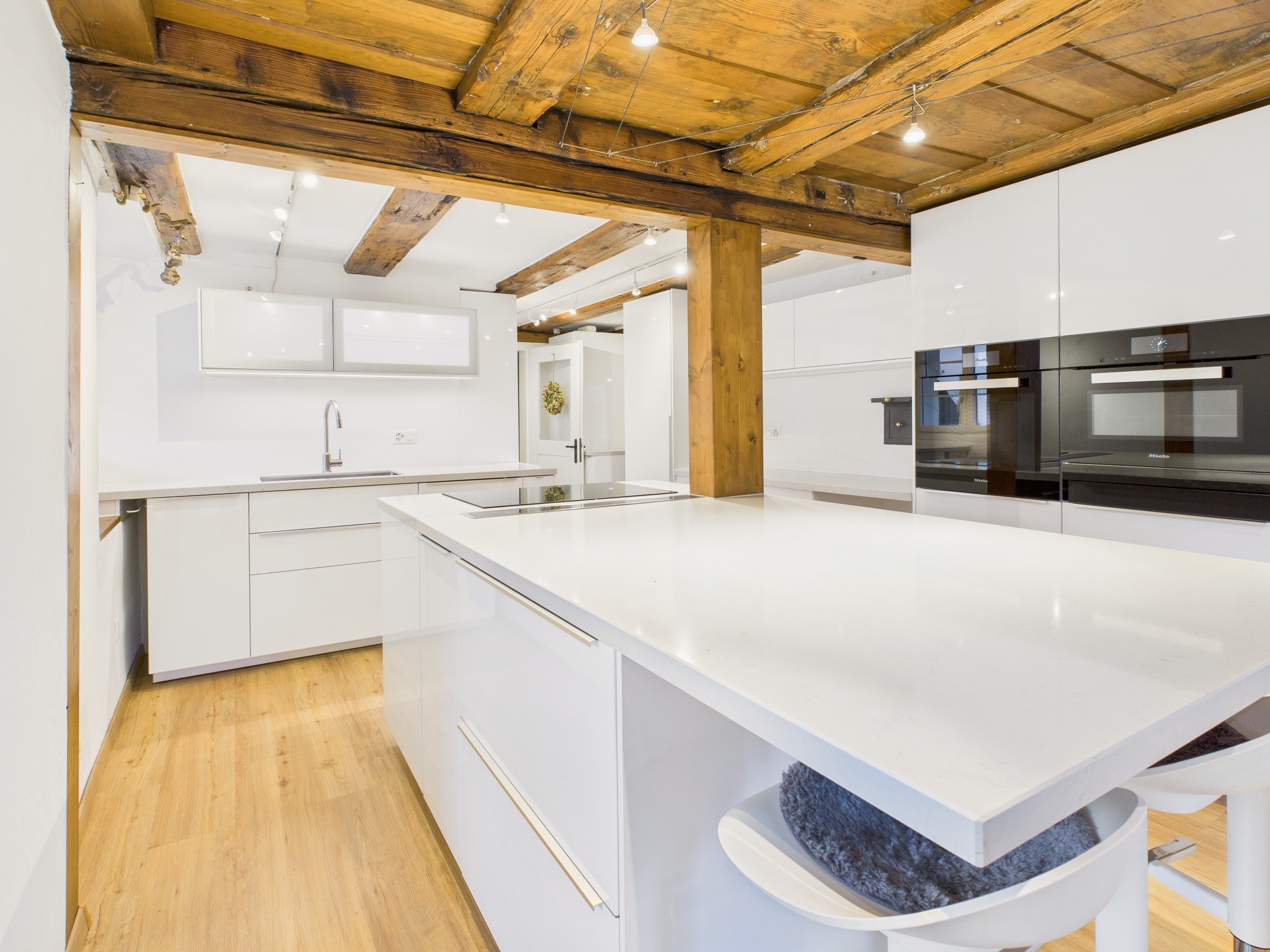 Moderne weiße Küche mit sichtbaren Holzbalken