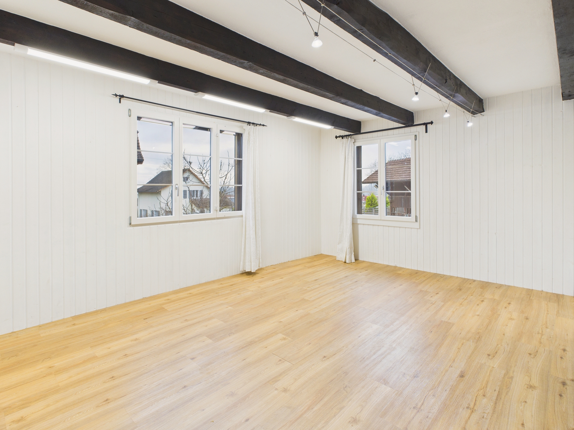 Leerer heller Raum mit Holzboden und sichtbaren Deckenbalken
