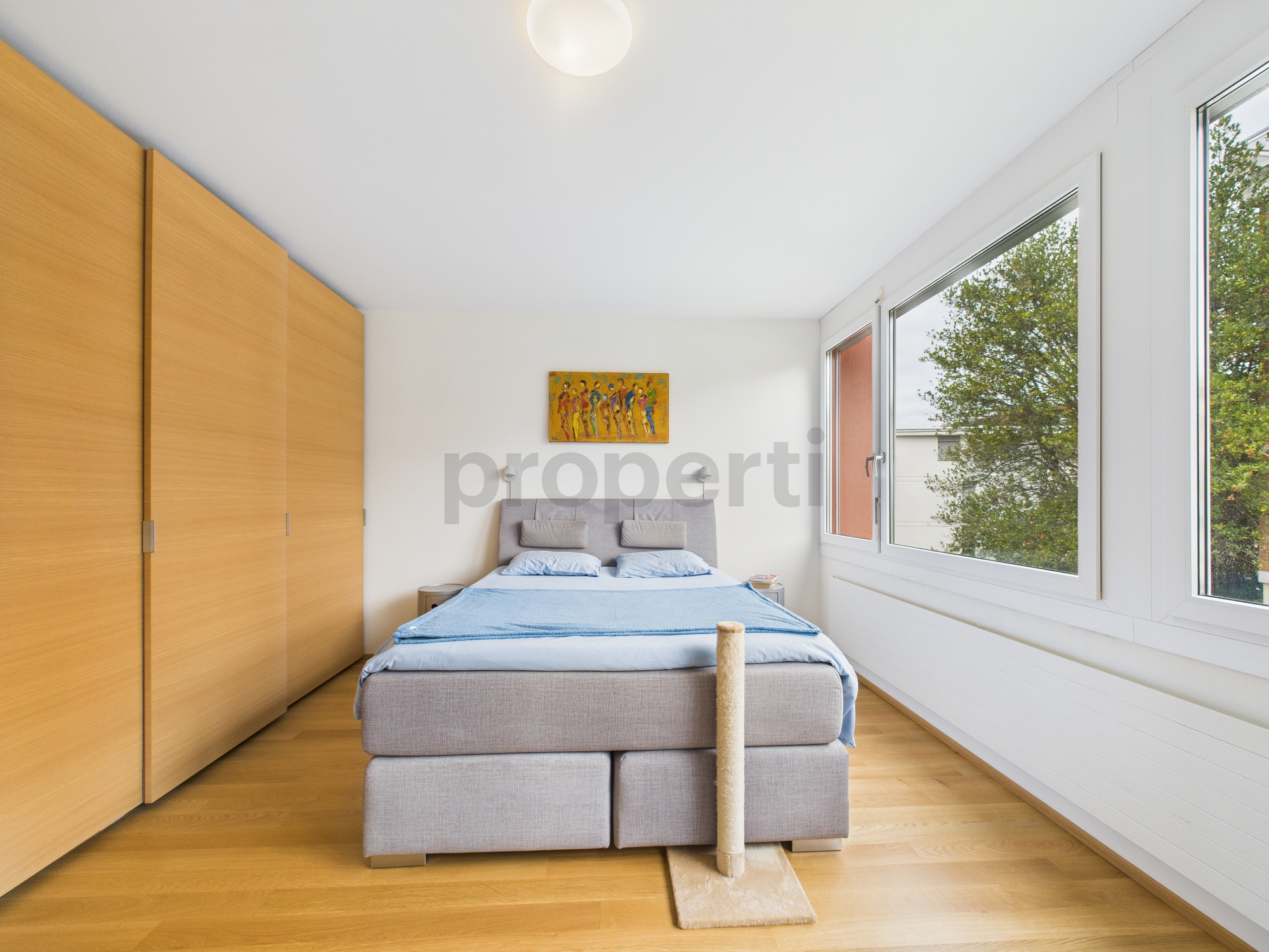 Helles Schlafzimmer mit Einbauschrank und großen Fenstern