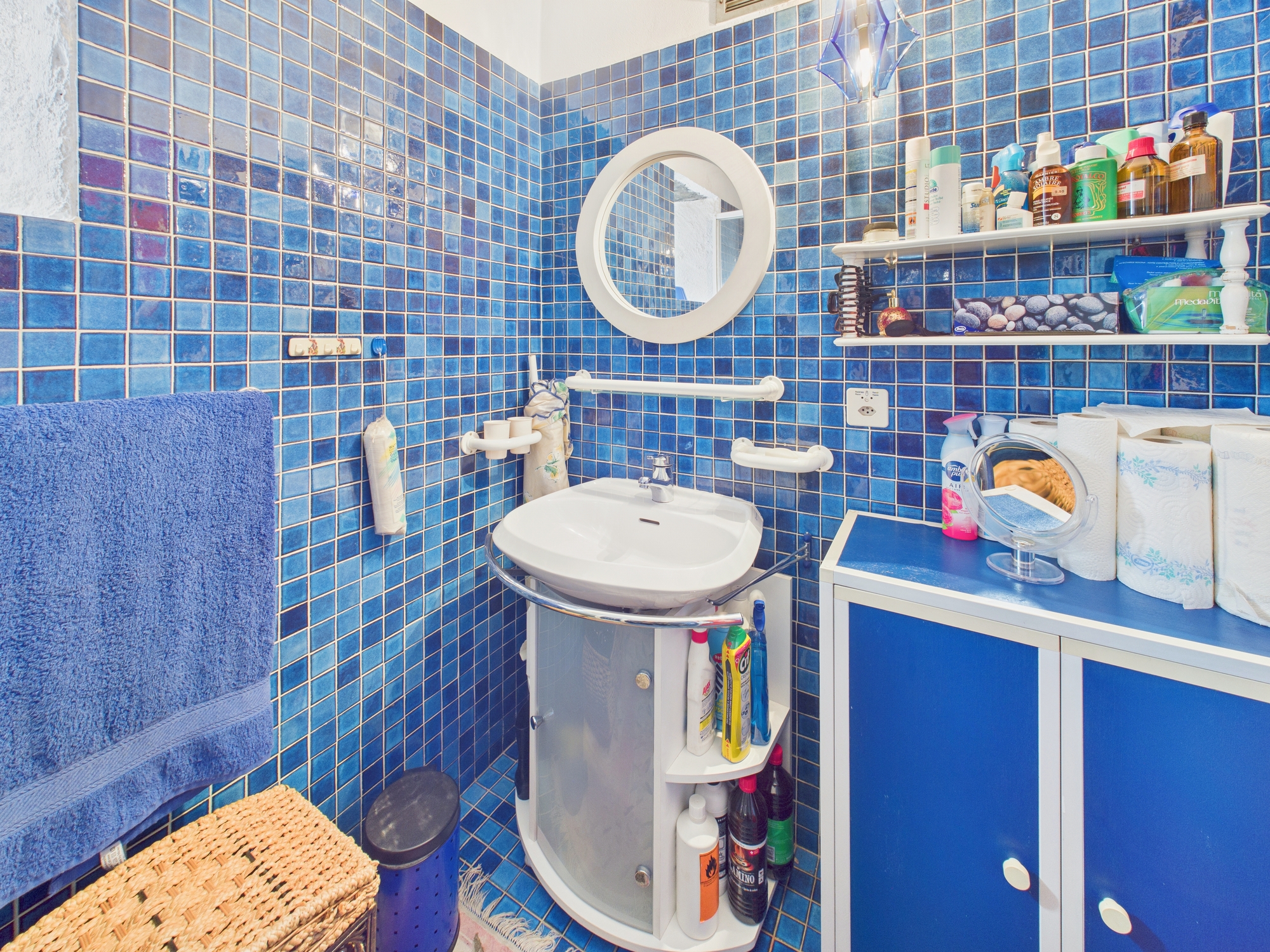 Blau gefliestes Badezimmer mit Waschbecken und Stauraum