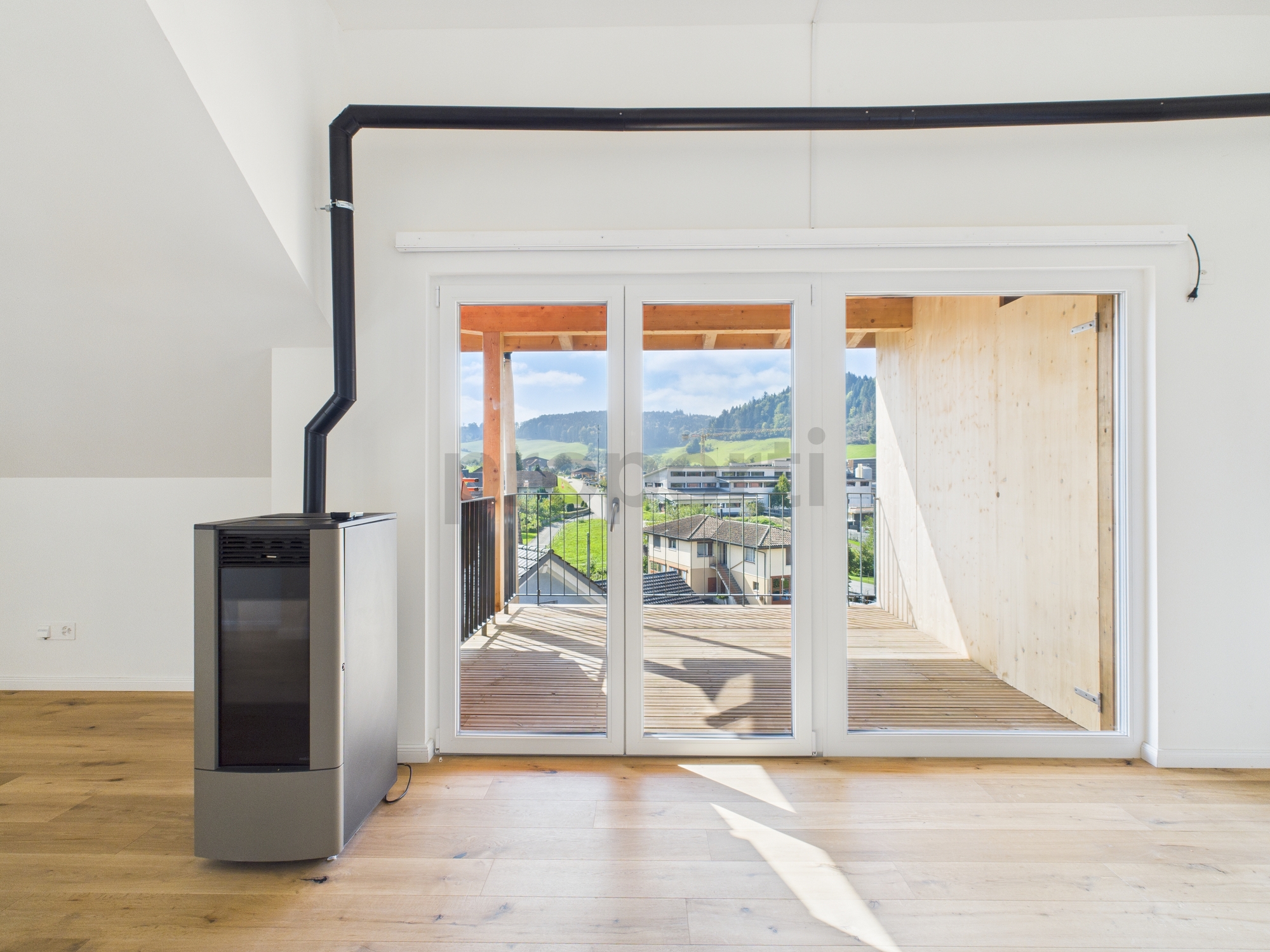 Heller Wohnraum mit Balkon- bzw. Terrassentür und Kaminofen
