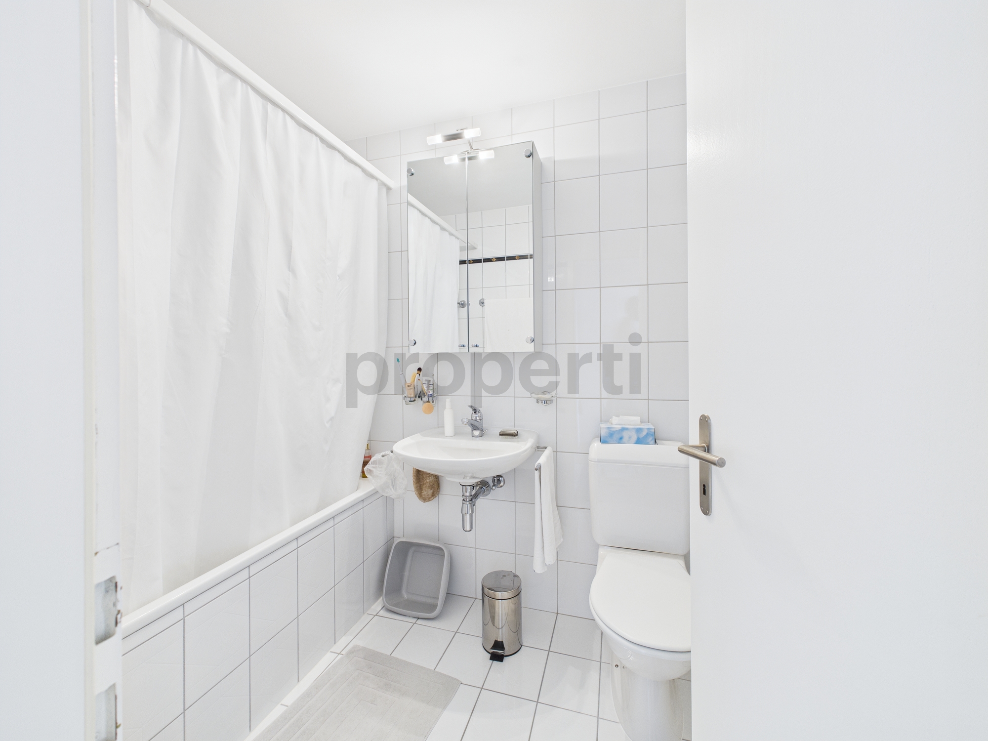 Kleines weißes Badezimmer mit Toilette und Waschbecken