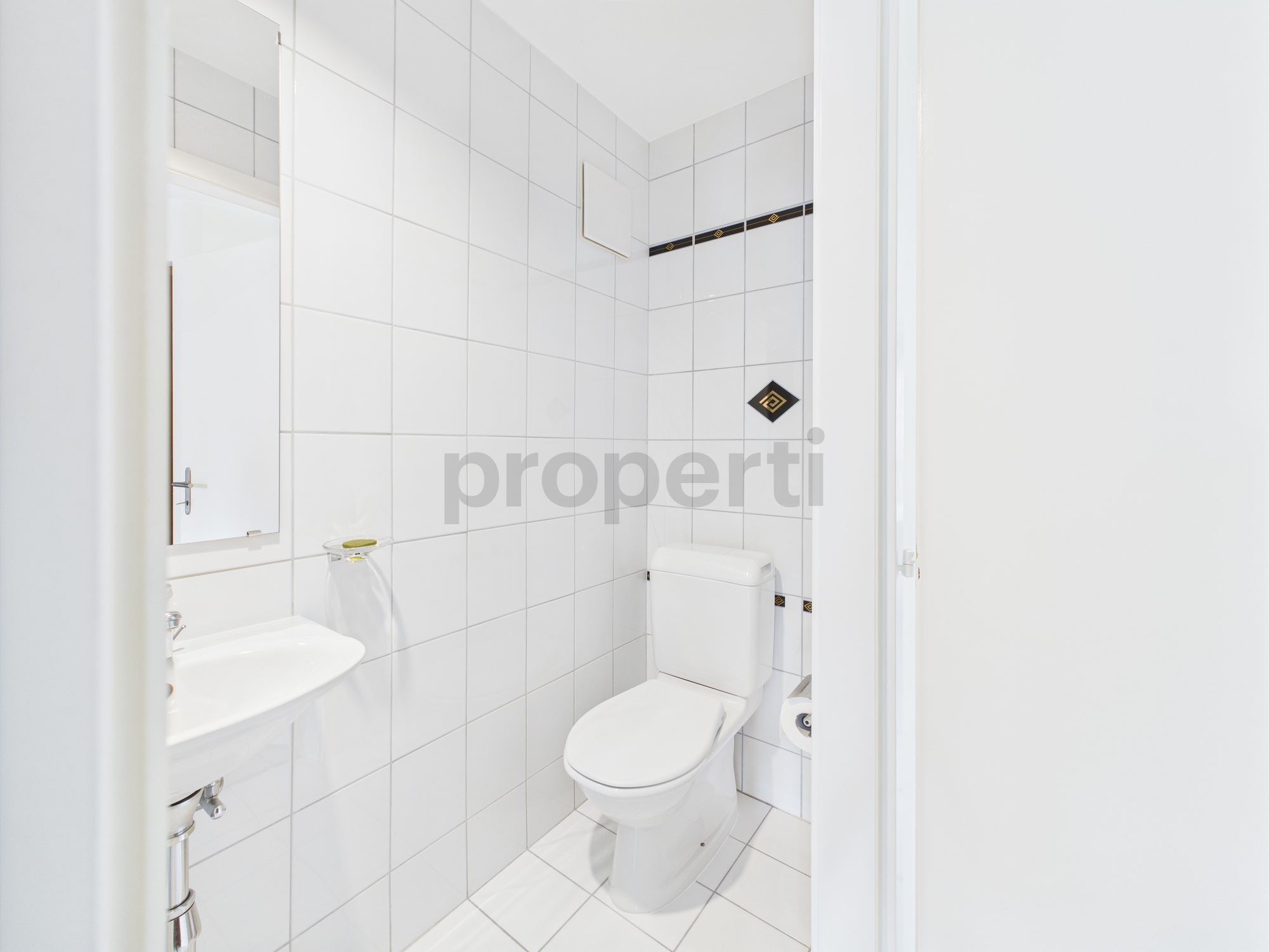 Gäste-WC mit weißer Fliesenverkleidung