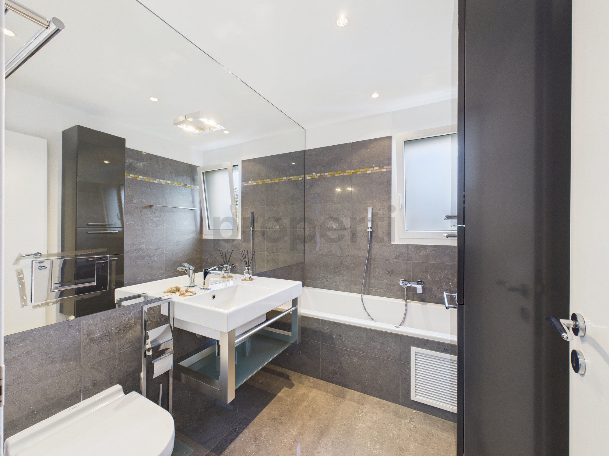 Modernes Badezimmer mit Badewanne und grauen Fliesen