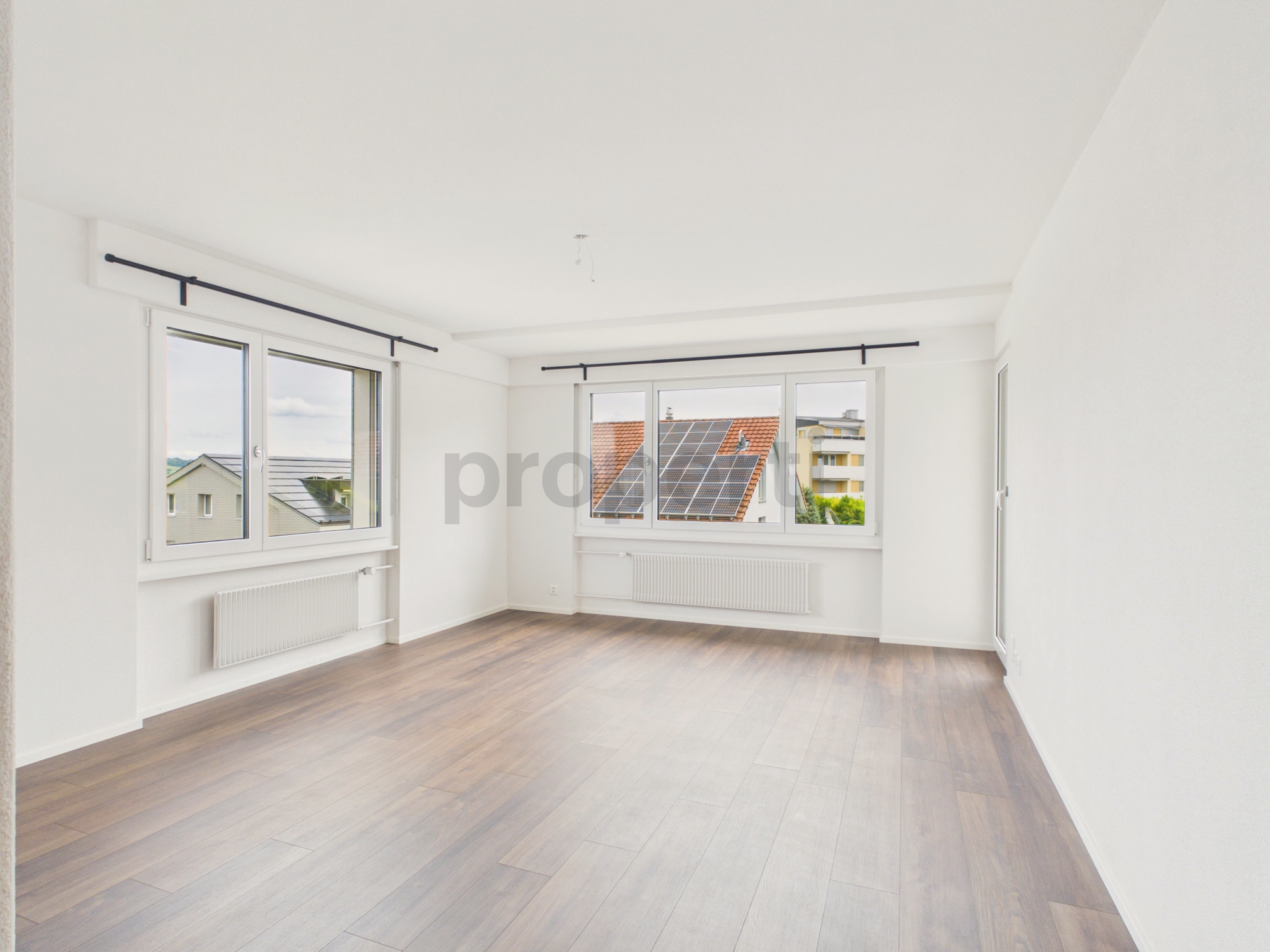 Heller leerer Wohnraum mit Blick auf Dächer und Solarpaneele
