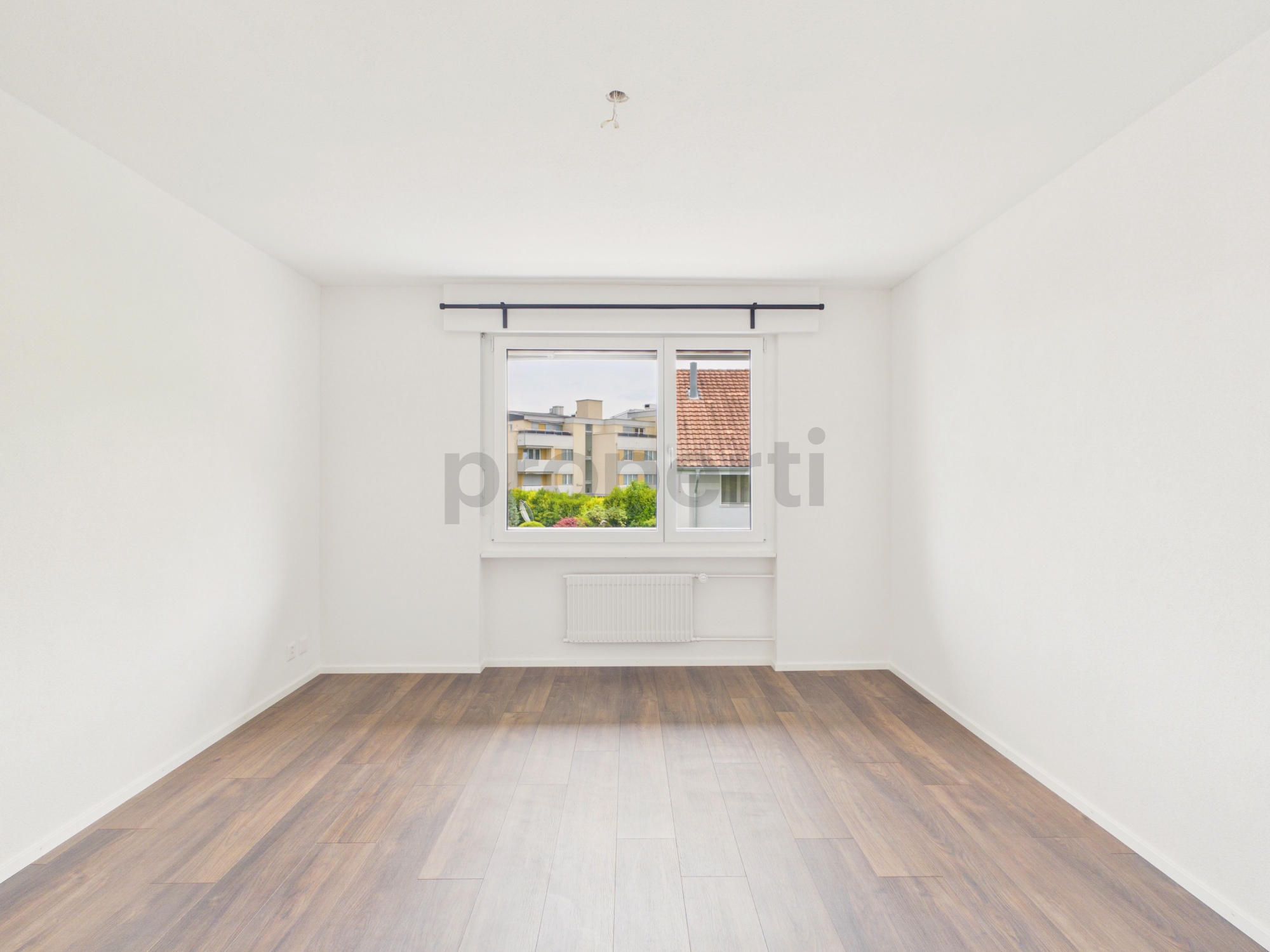 Leerer heller Raum mit Fenster und Holzoptik-Boden