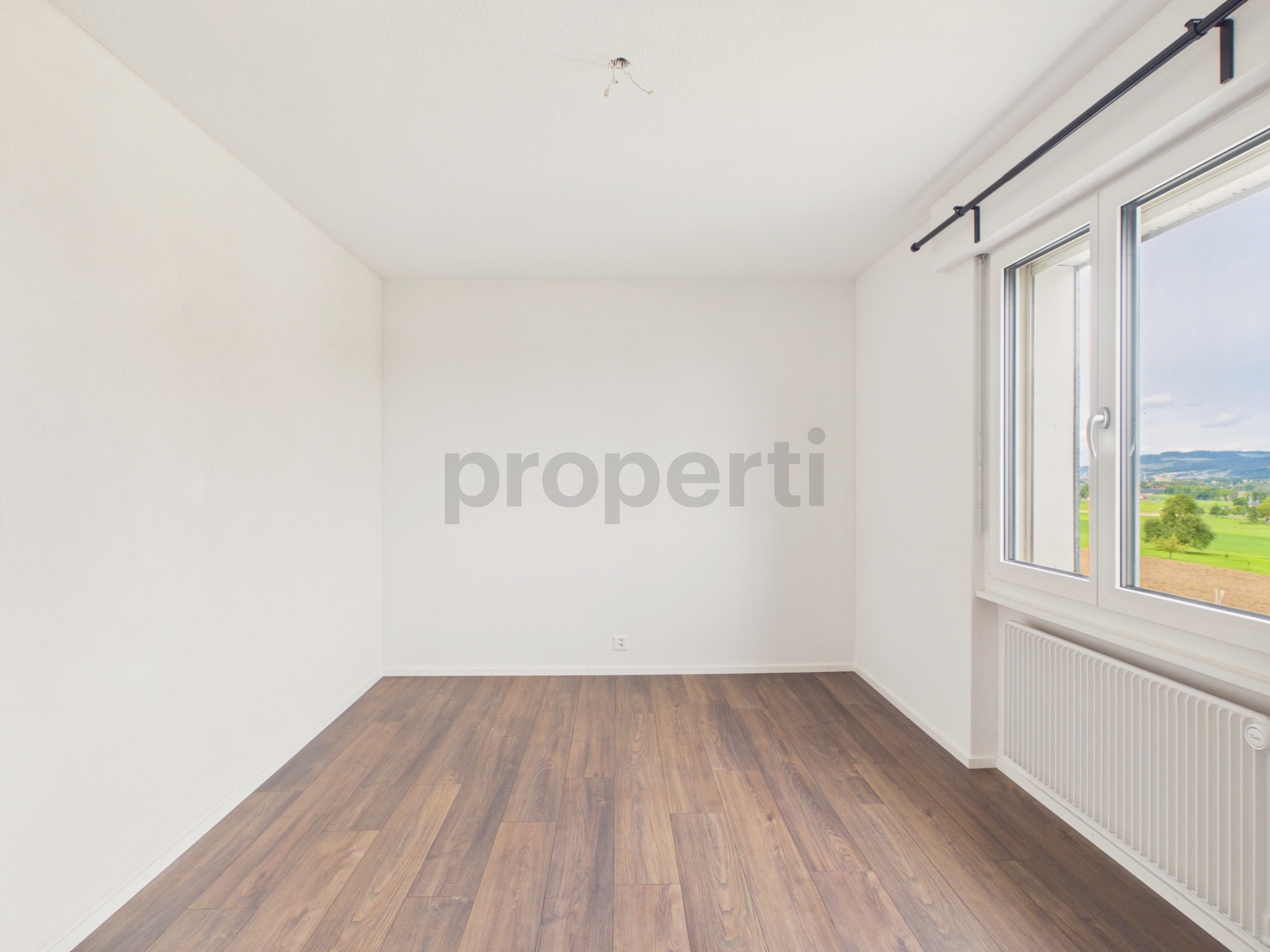 Leeres, helles Zimmer mit Holzoptikboden