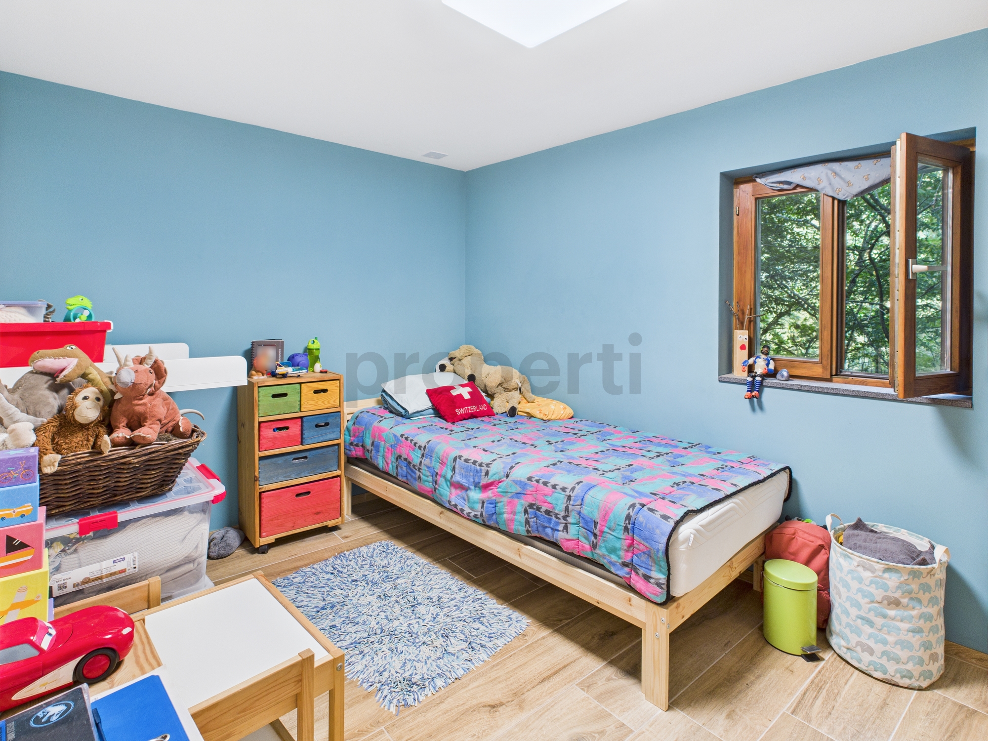 Kinderzimmer mit blau gestrichenen Wänden und Holzfenster