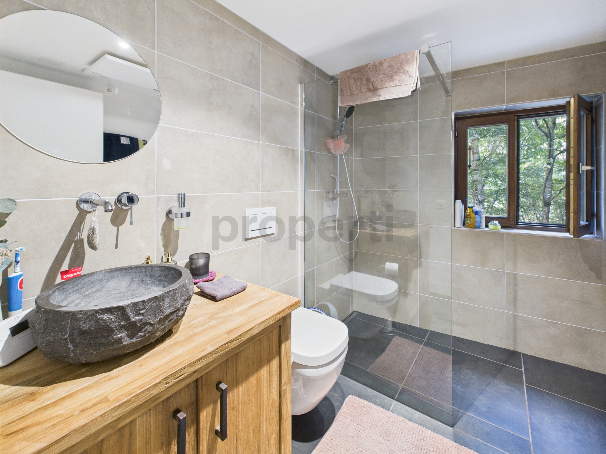 Modernes Badezimmer mit Natursteinwaschbecken und Glasdusche