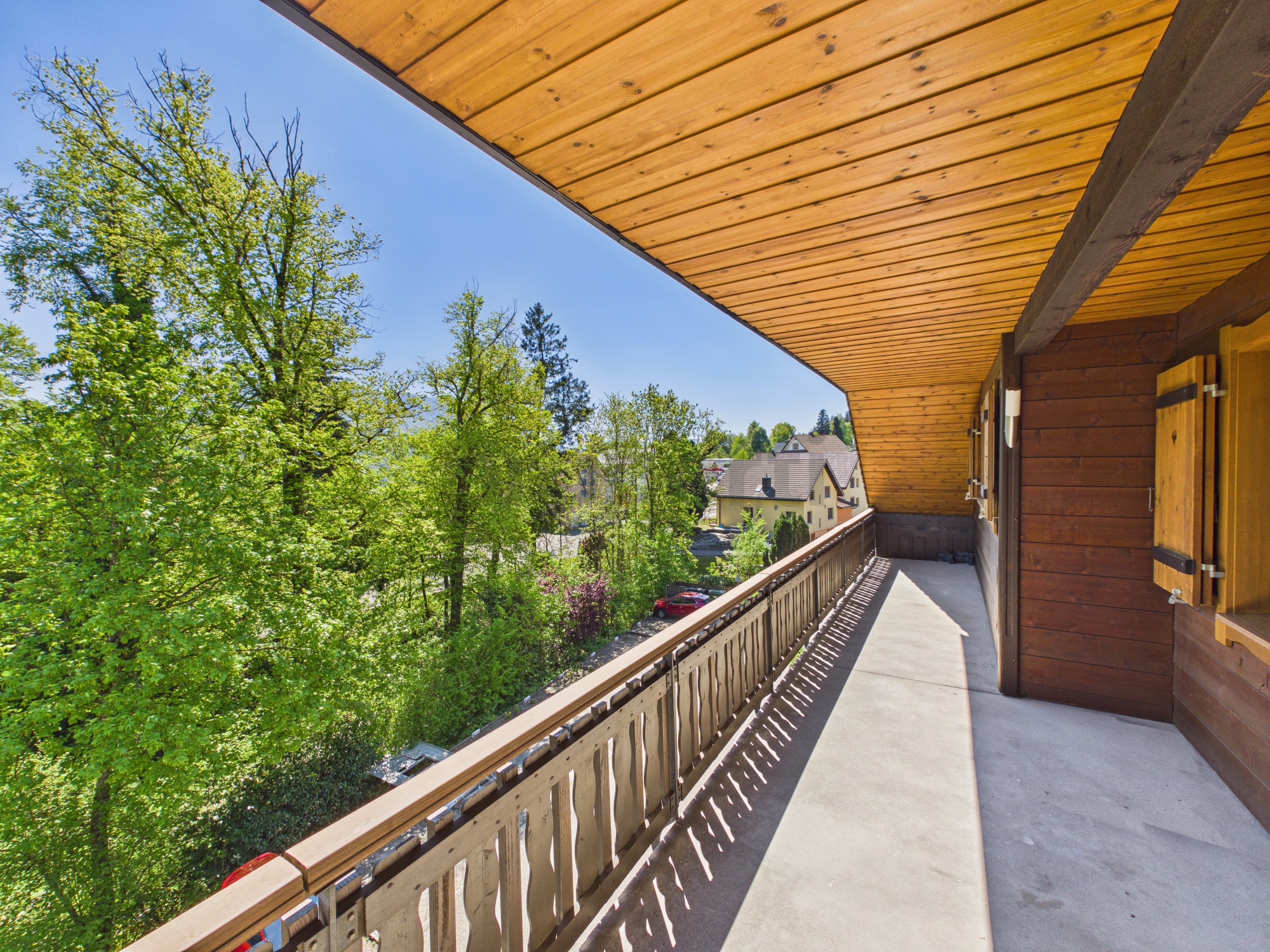 Überdachter Balkon mit Holzverkleidung und Ausblick ins Grüne