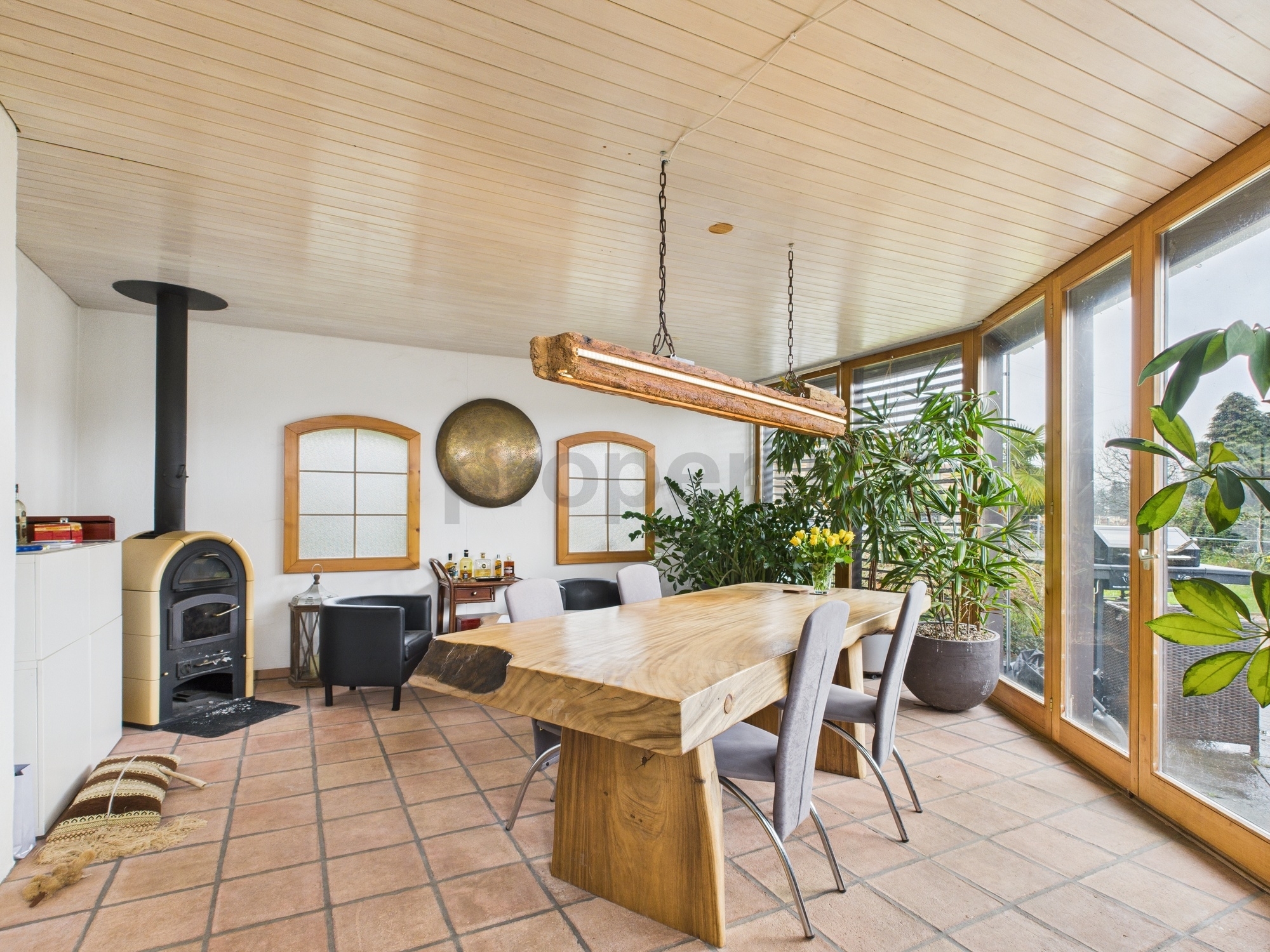 Essbereich mit Holzofen und großen Fensterfronten