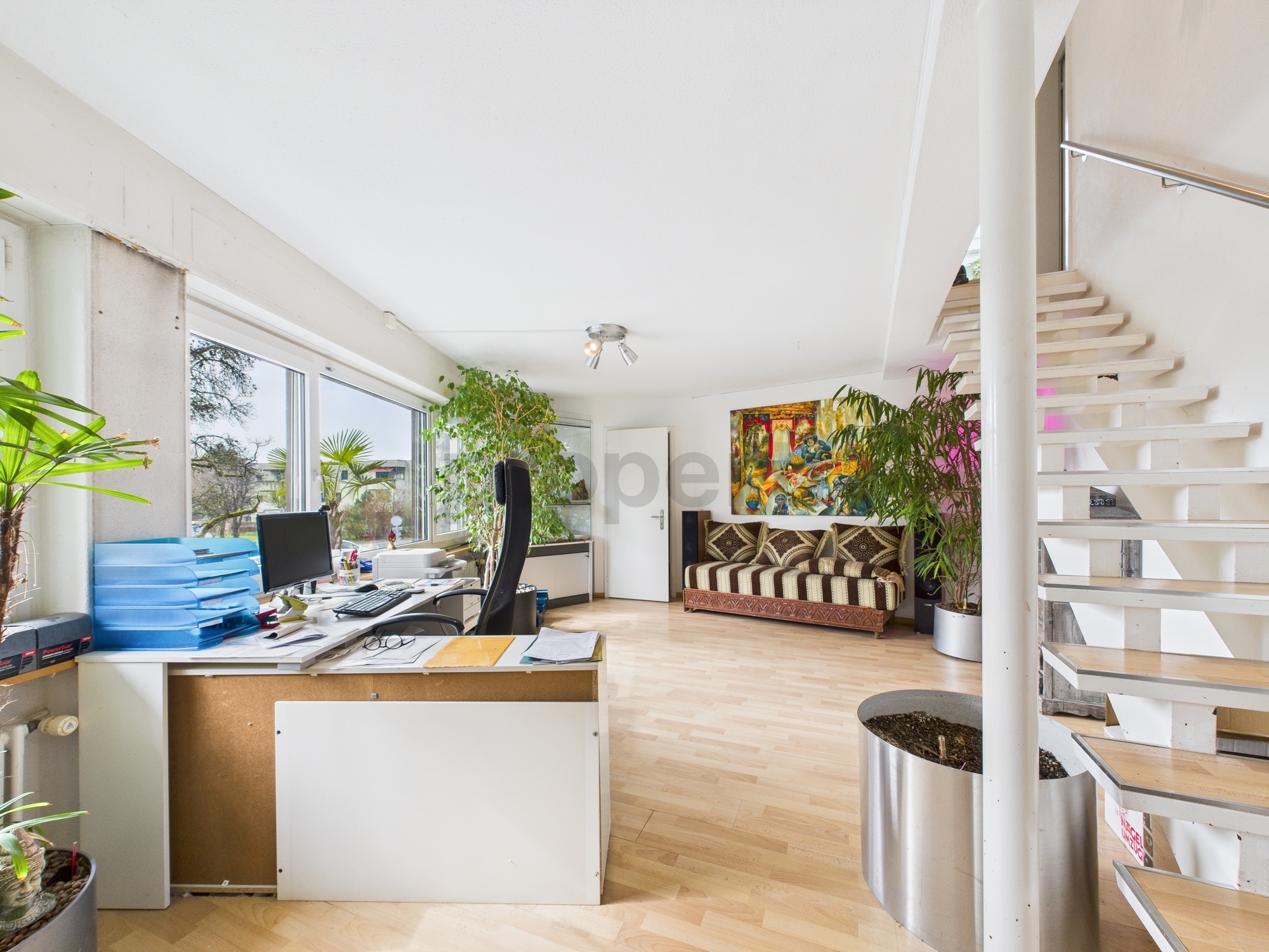 Helles Loft-Büro mit Treppe und Pflanzen