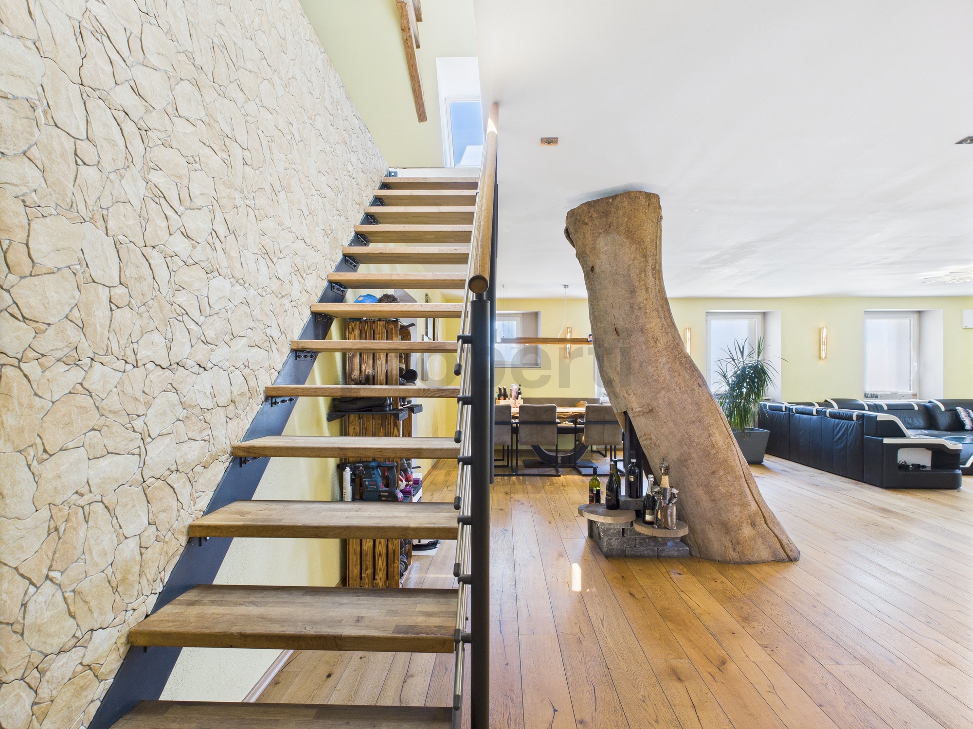 Offener Wohnbereich mit Treppe und Natursteinwand