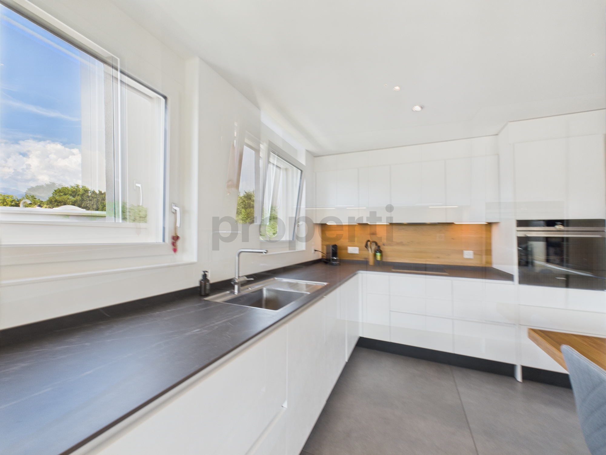 Moderne weiße Küche mit großen Fenstern