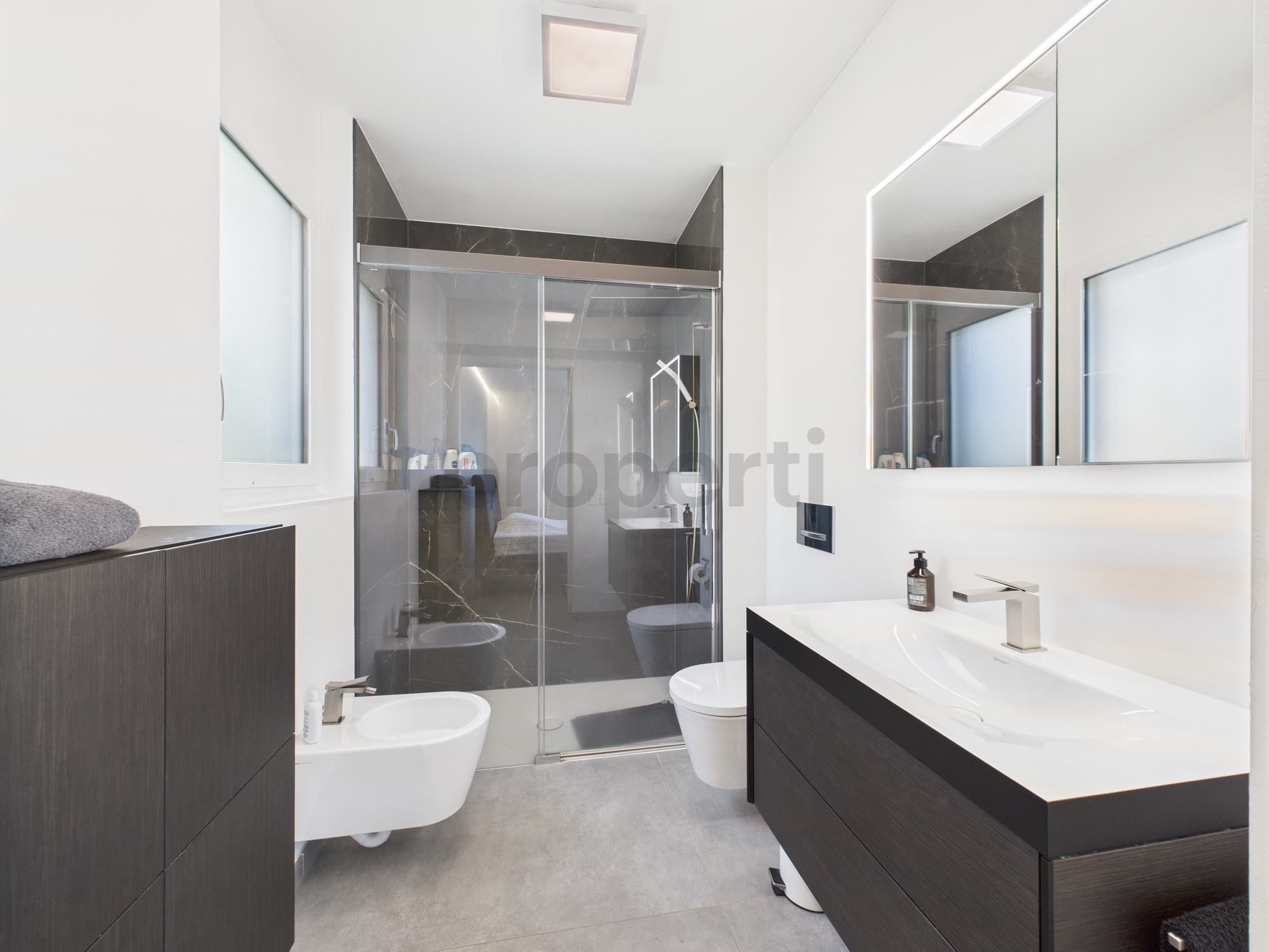 Modernes Badezimmer mit dunklem Mobiliar