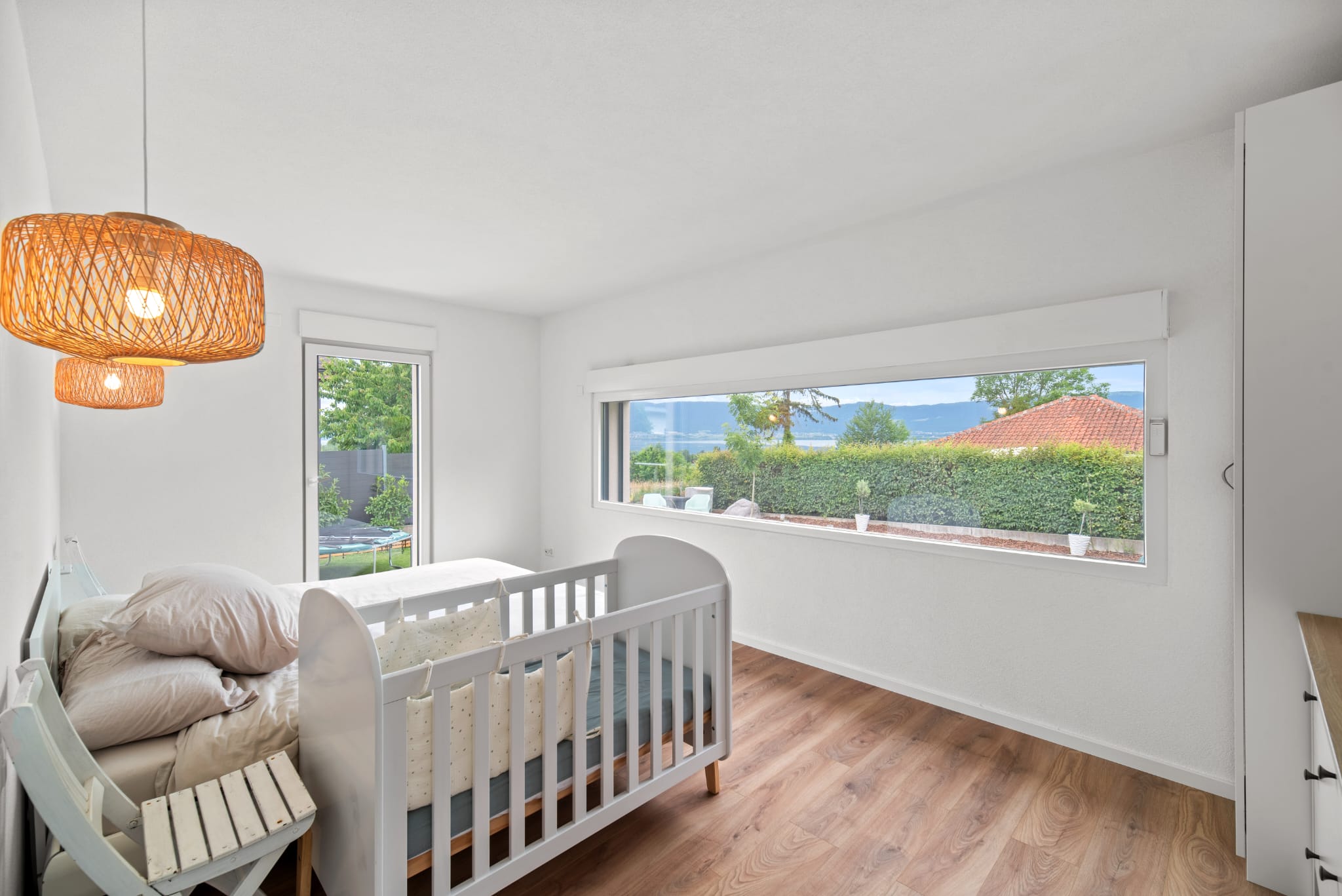 Helles Kinderzimmer mit großem Fenster und Blick ins Grüne