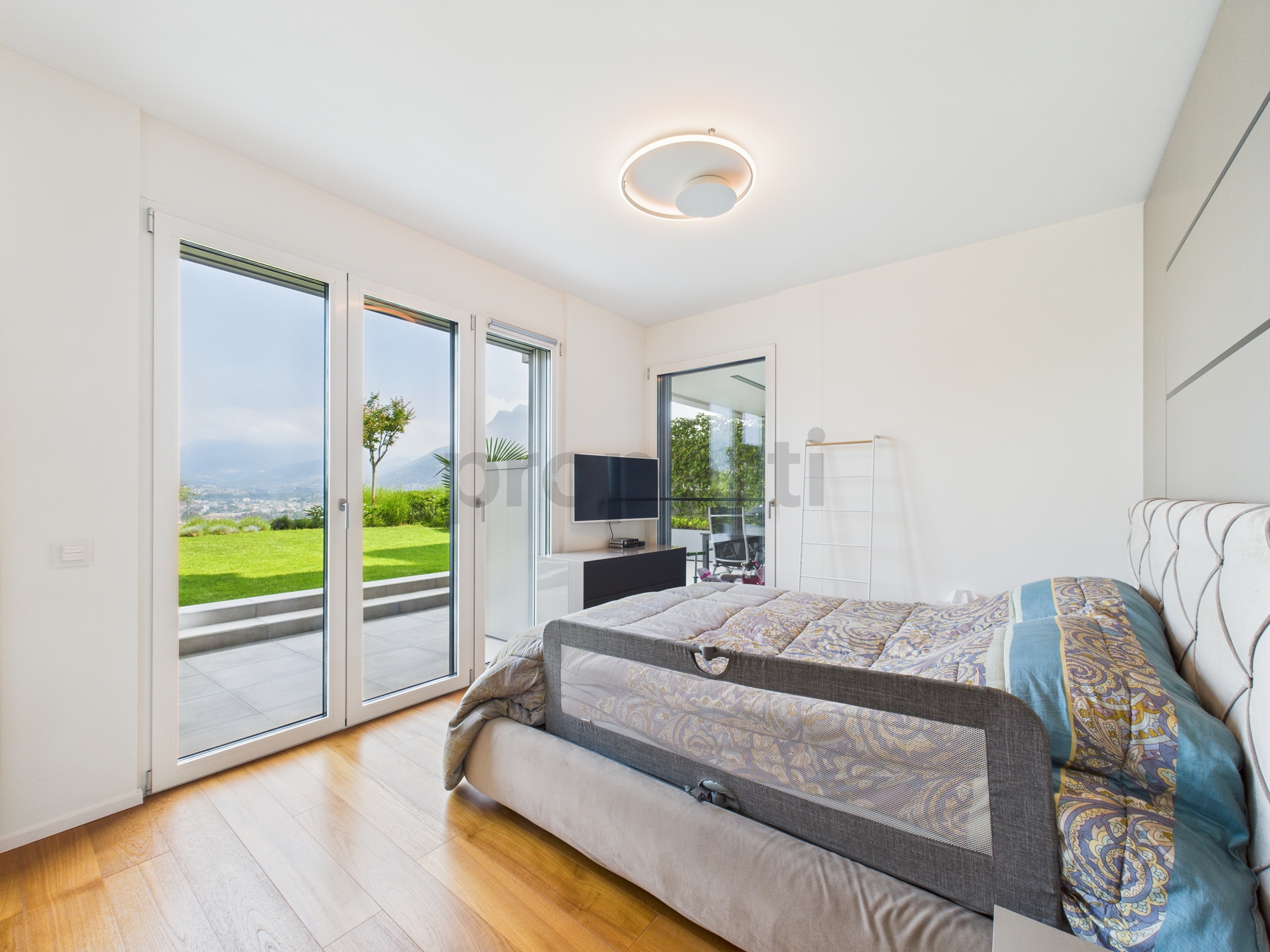 Modernes Schlafzimmer mit großer Glasfront und Gartenblick