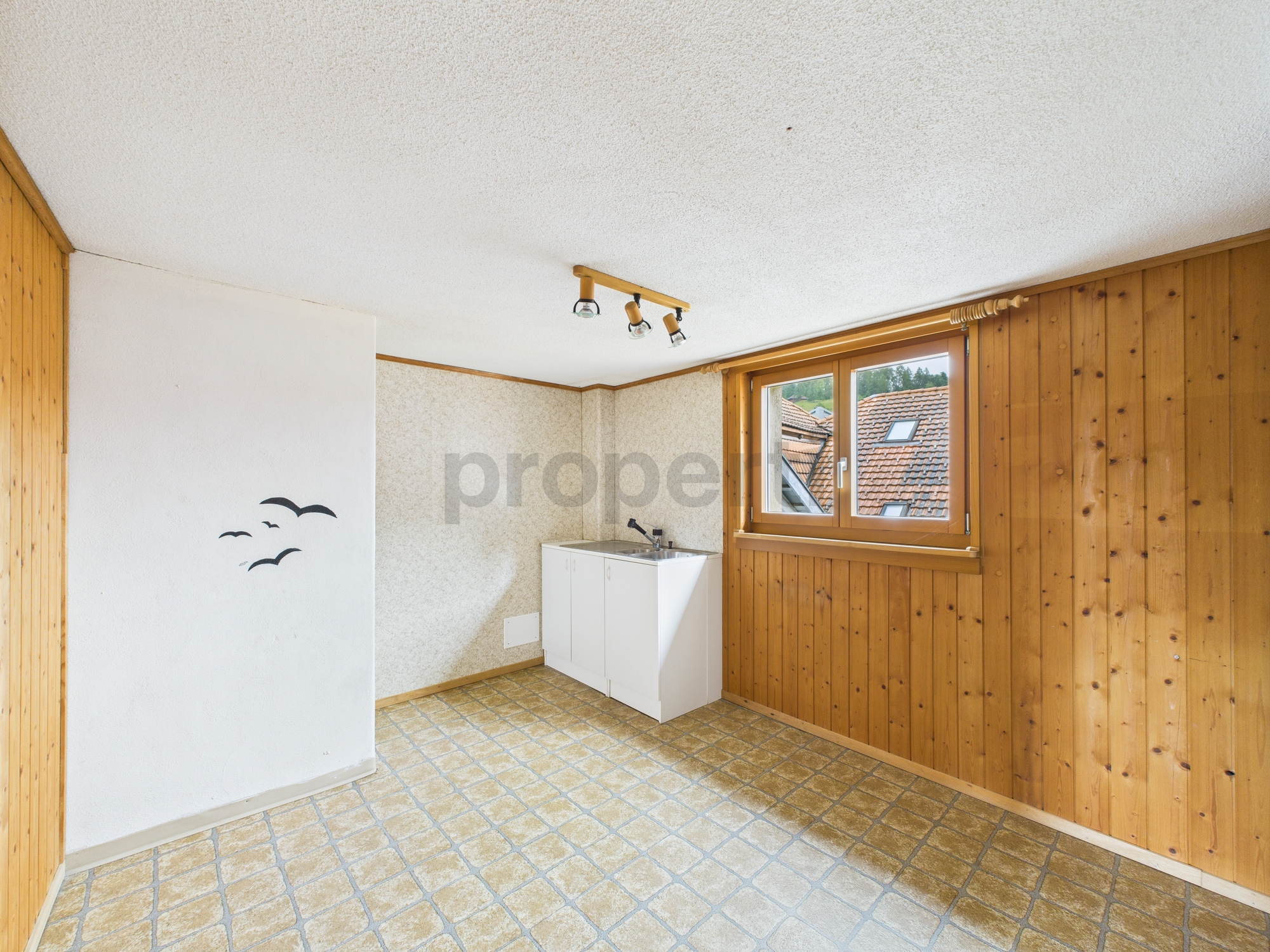 Leerer Raum mit Holzvertäfelung und kleinem Spülbereich