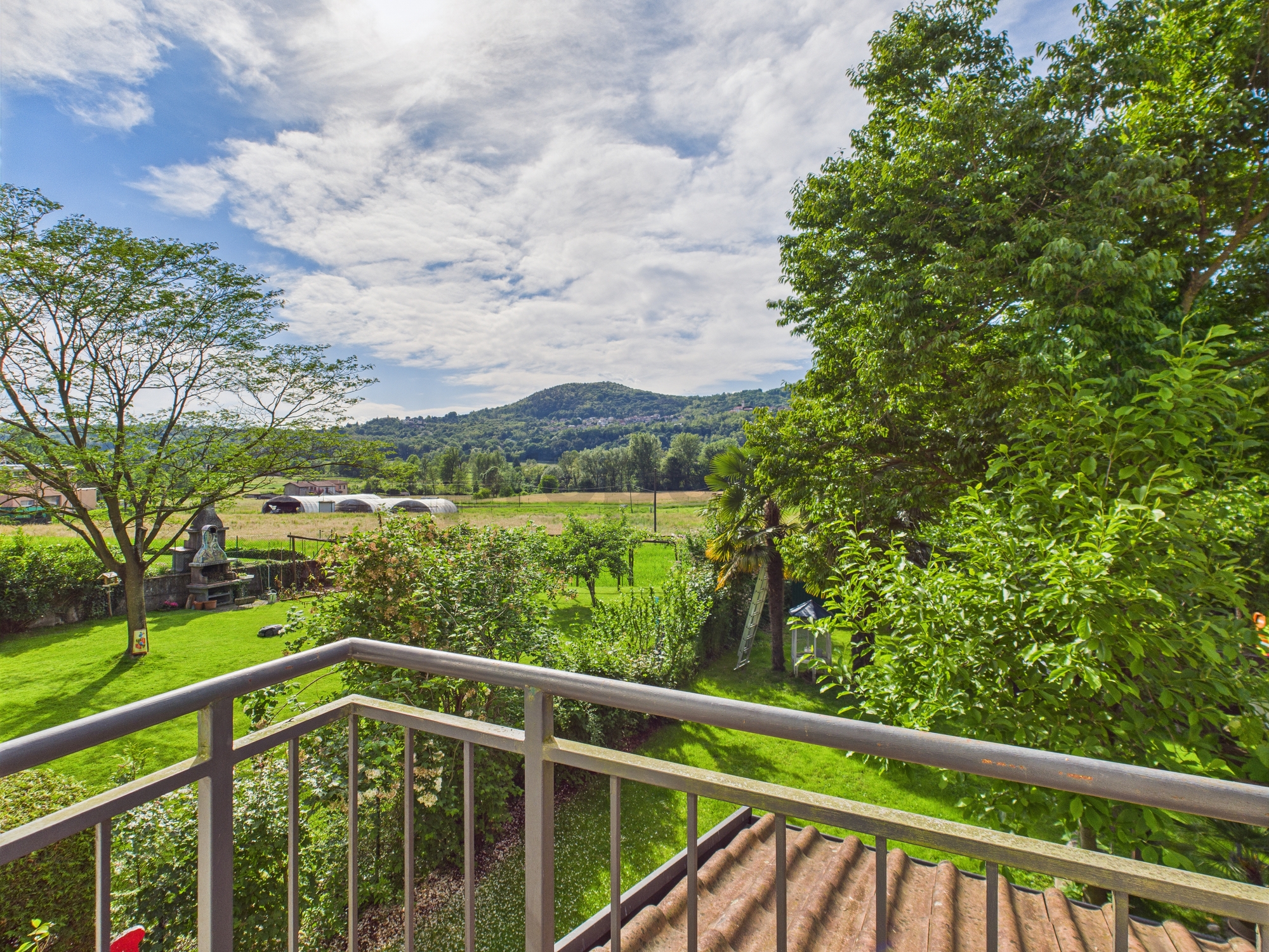 Blick über einen Garten auf eine hügelige Landschaft