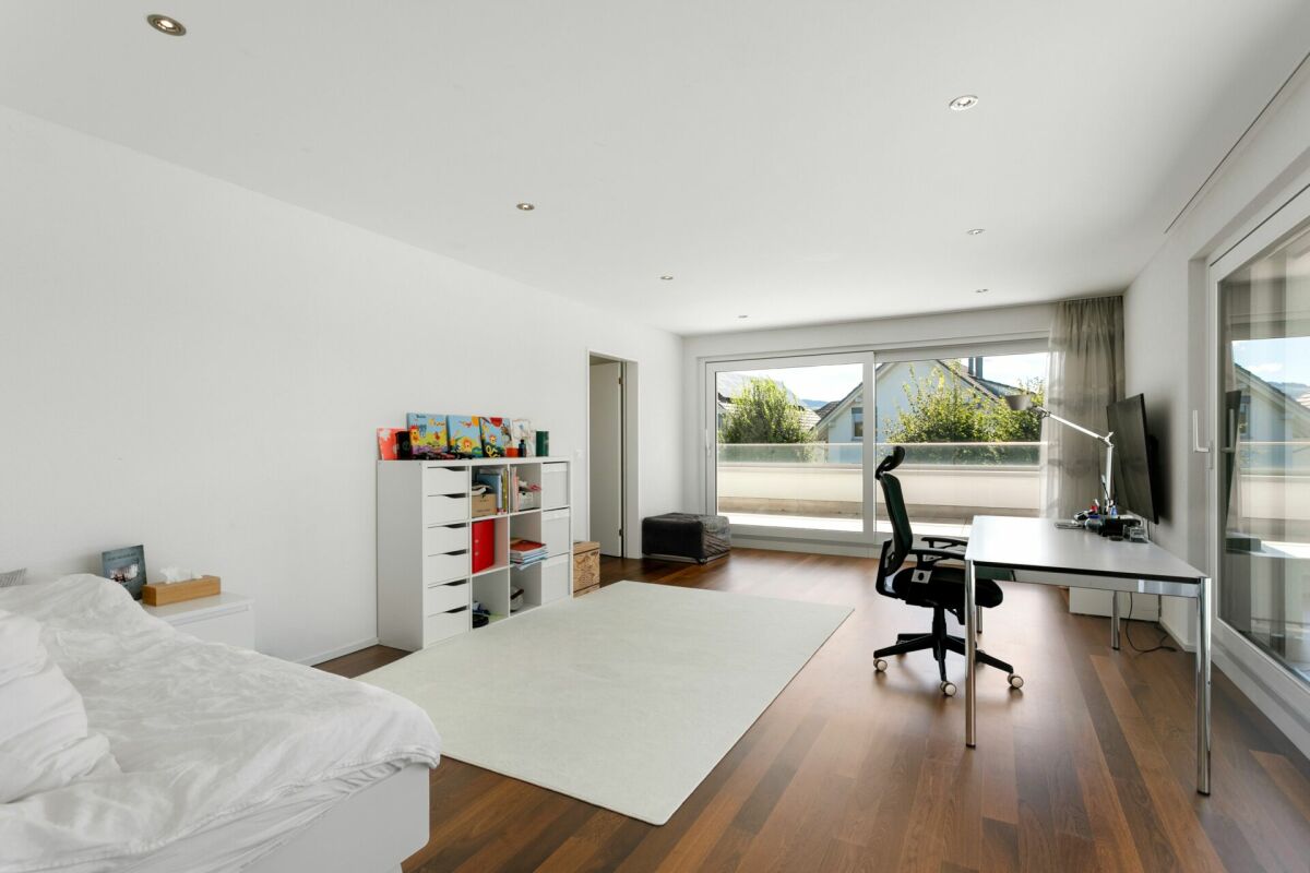 Helles Schlafzimmer mit Arbeitsbereich und Balkonzugang