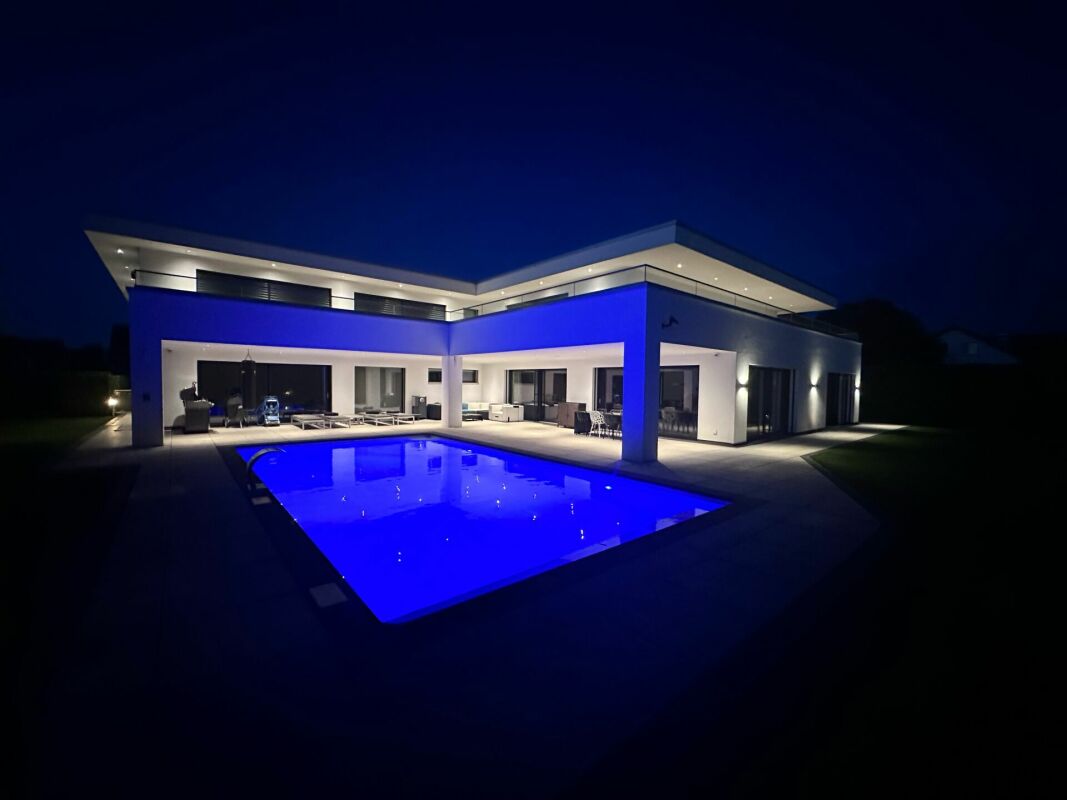 Moderne Villa mit beleuchtetem Pool bei Nacht