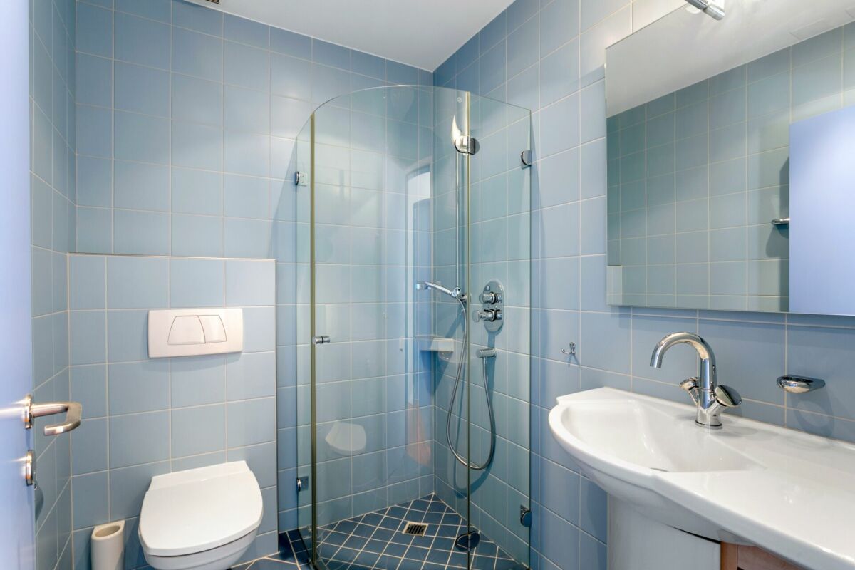 Modernes blau gefliestes Bad mit Dusche und WC