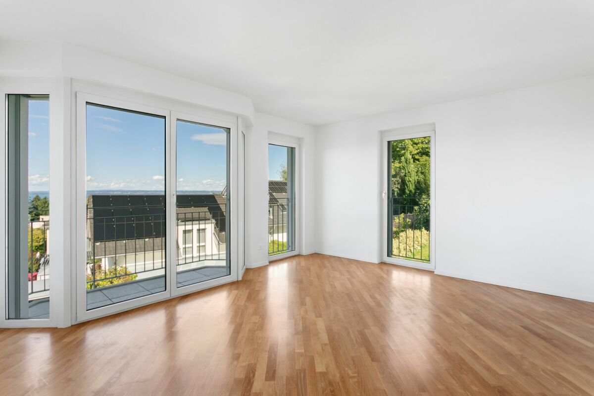 Heller leerer Wohnraum mit großen Fenstern und Balkonblick