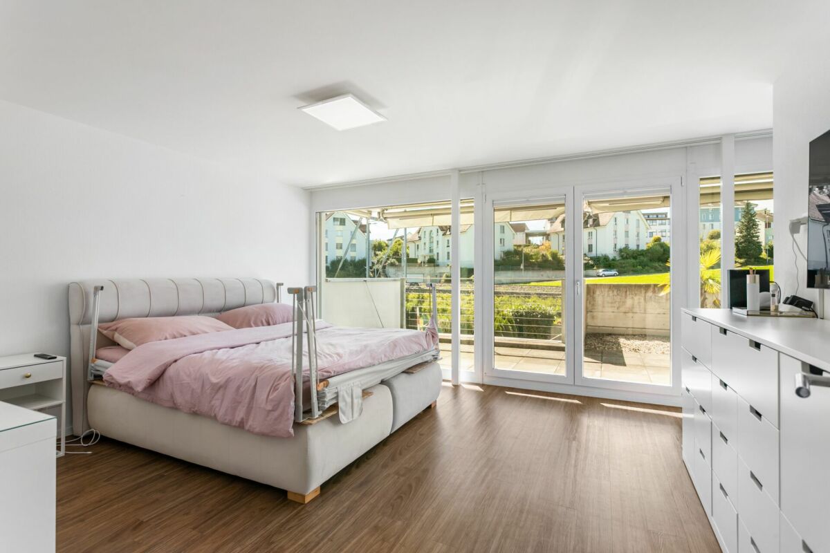 Helles Schlafzimmer mit großflächiger Verglasung und Balkonblick