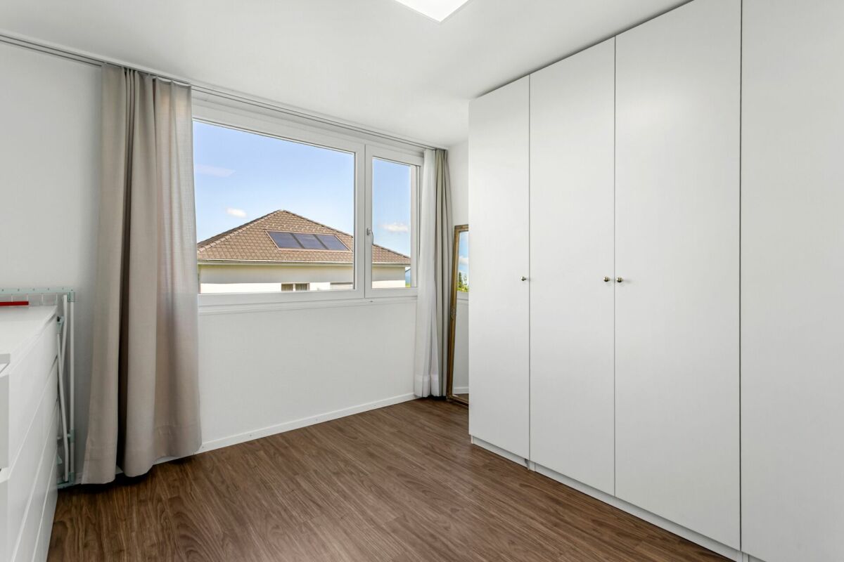 Helles Schlafzimmer mit großem Fenster und Einbauschrank