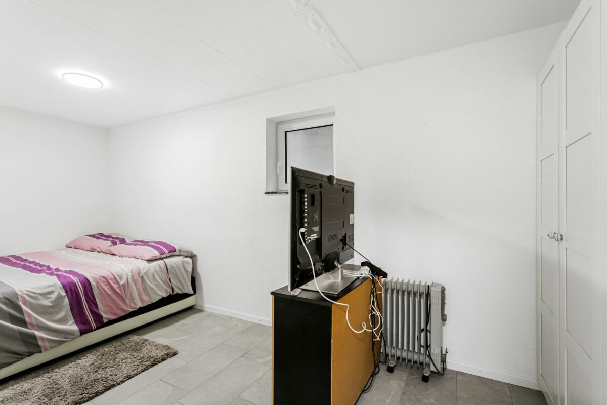 Schlichtes Schlafzimmer mit Fernseher und Heizkörper