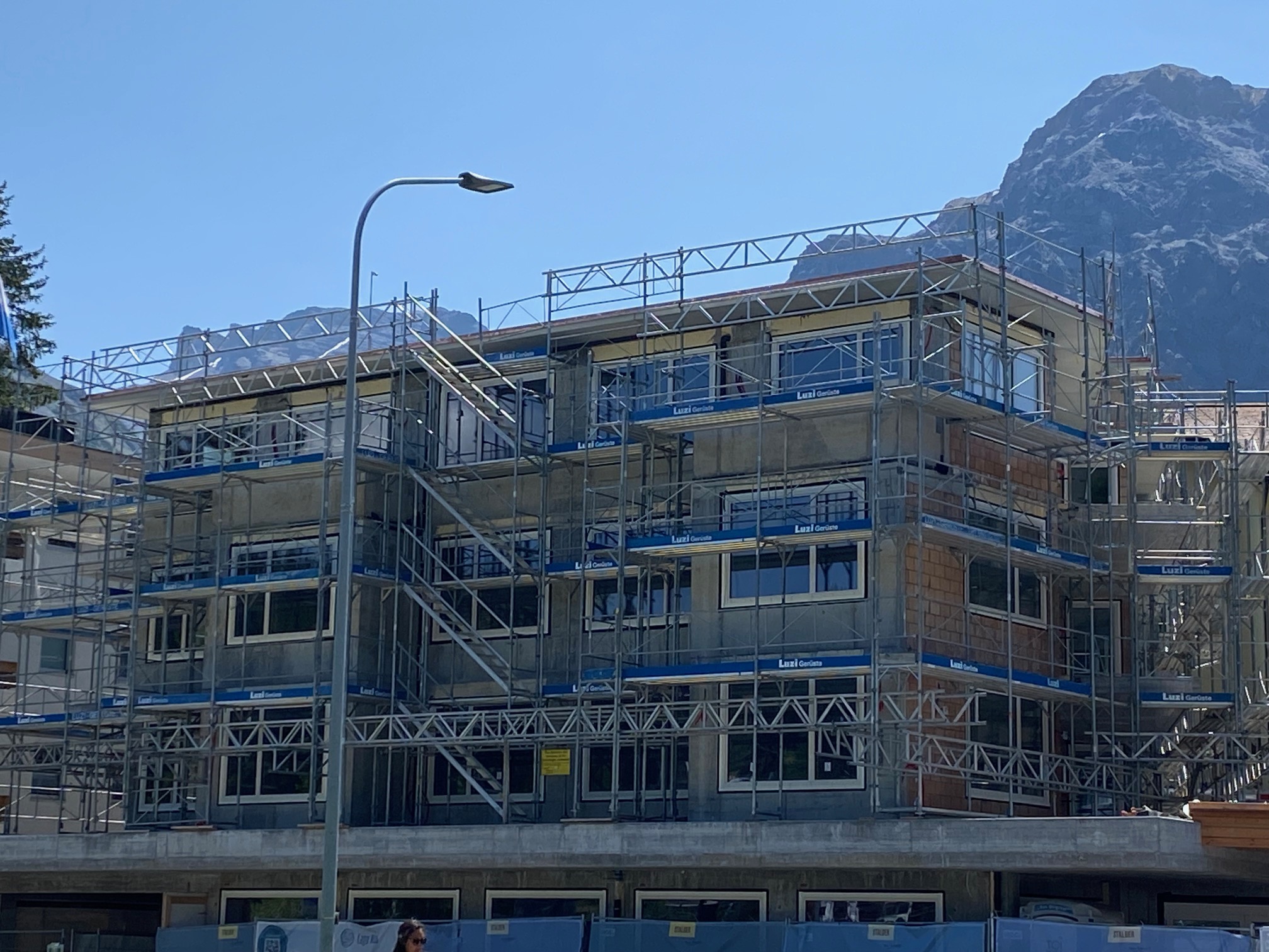 Wohngebäude im Bau mit Gerüst vor Bergkulisse