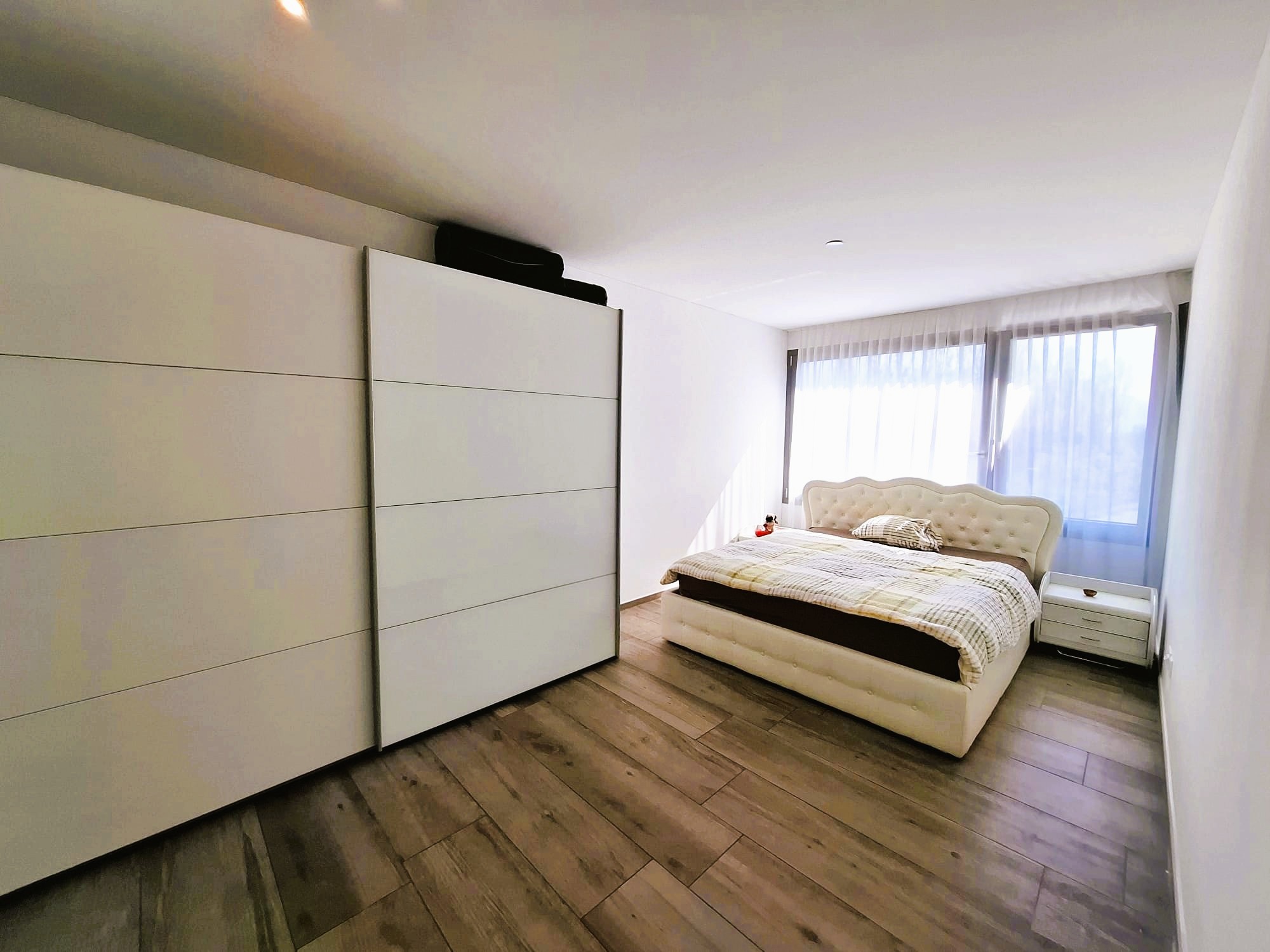 Helles Schlafzimmer mit Einbauschrank und gepolstertem Bett