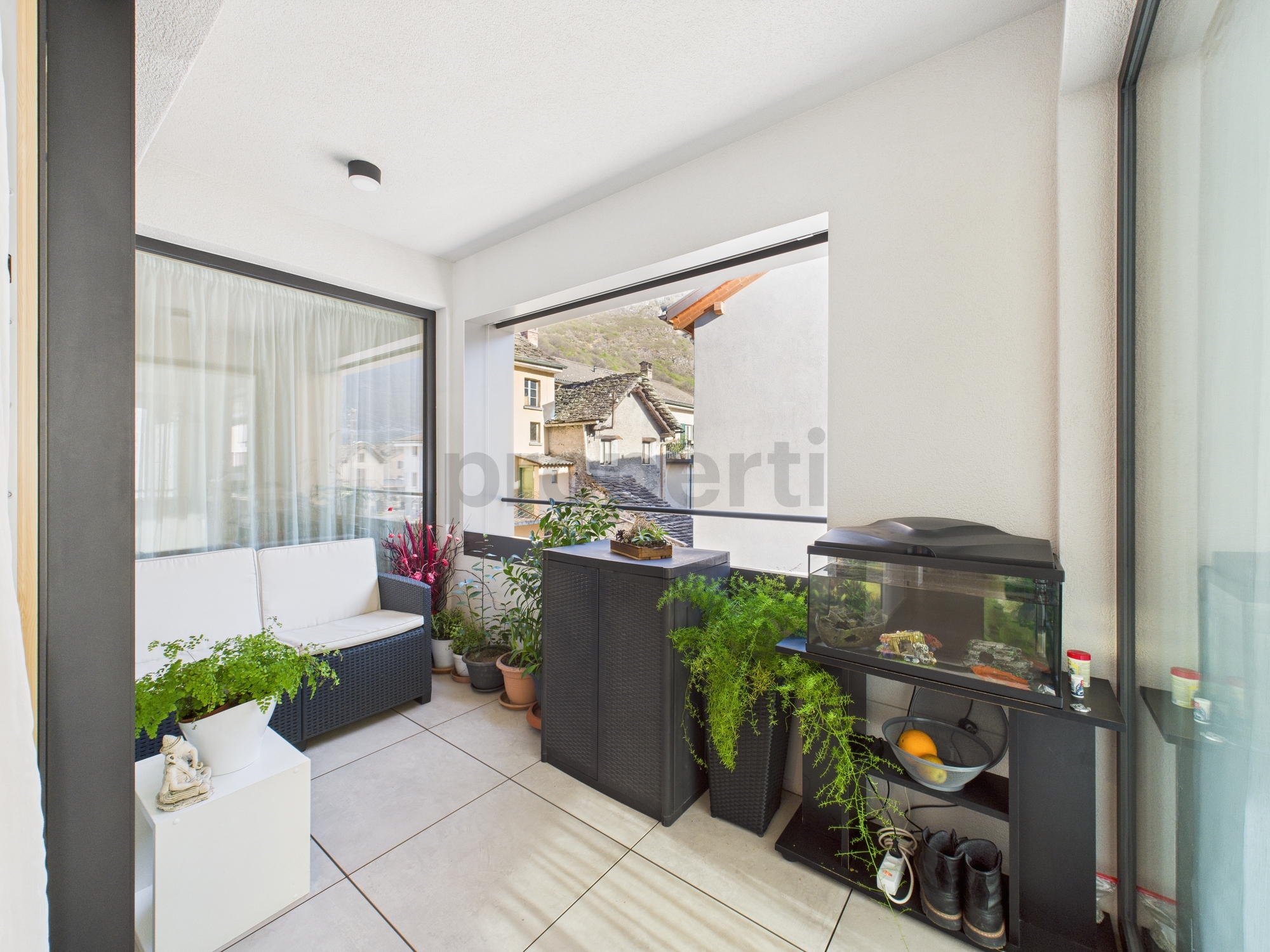 Überdachter Balkon mit Sitzbereich und Pflanzen