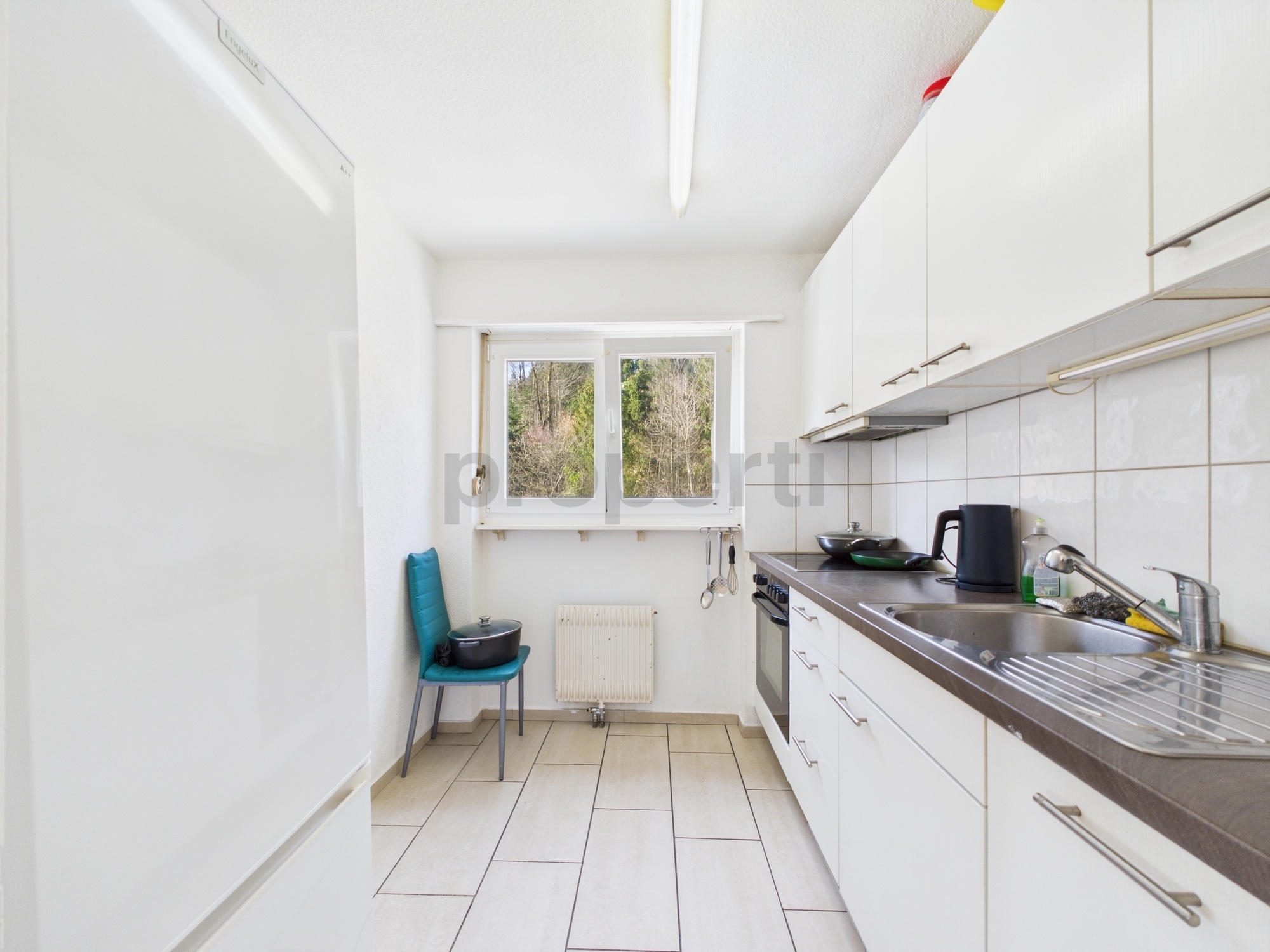 Schmale weiße Küche mit Fenster